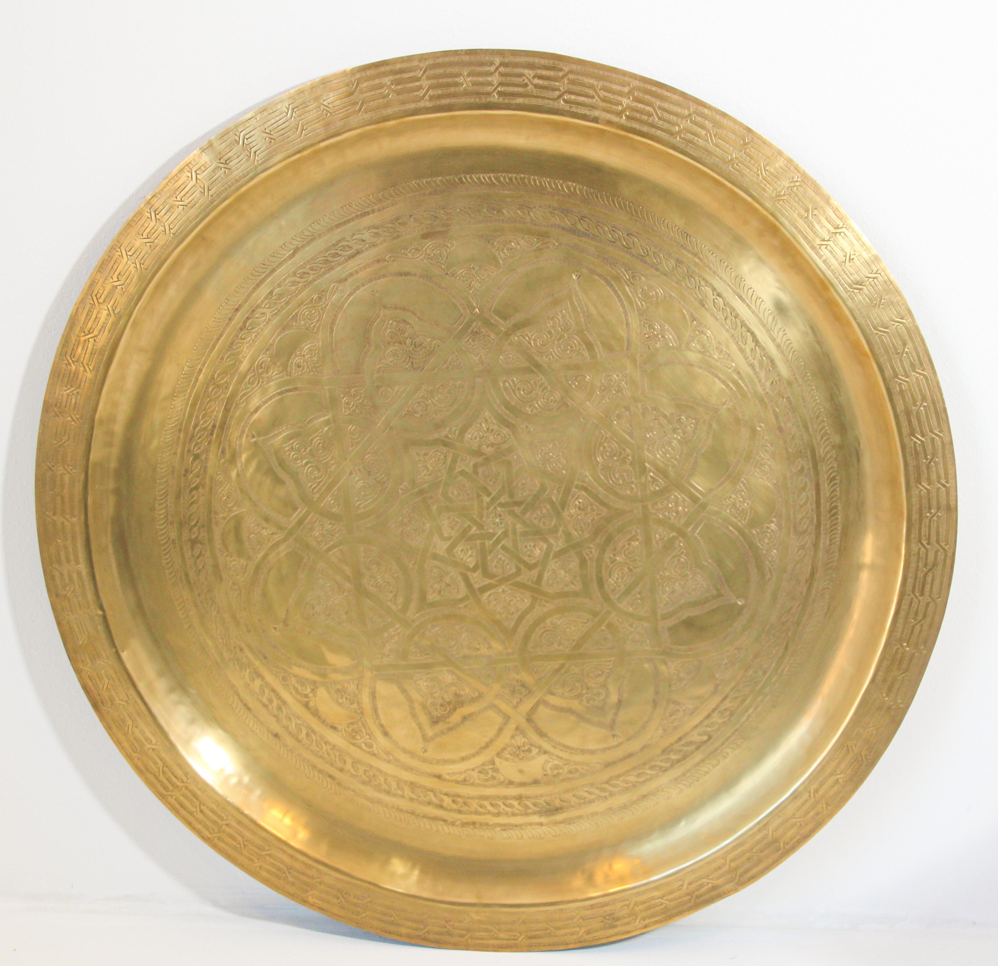 Moroccan large metal polished brass tray platter.
Polished decorative metal brass tray with very fine intricate designs.
Finley hand-hammered and chiseled in floral and geometrical Moorish designs with a star in the middle.
Heavy brass metal