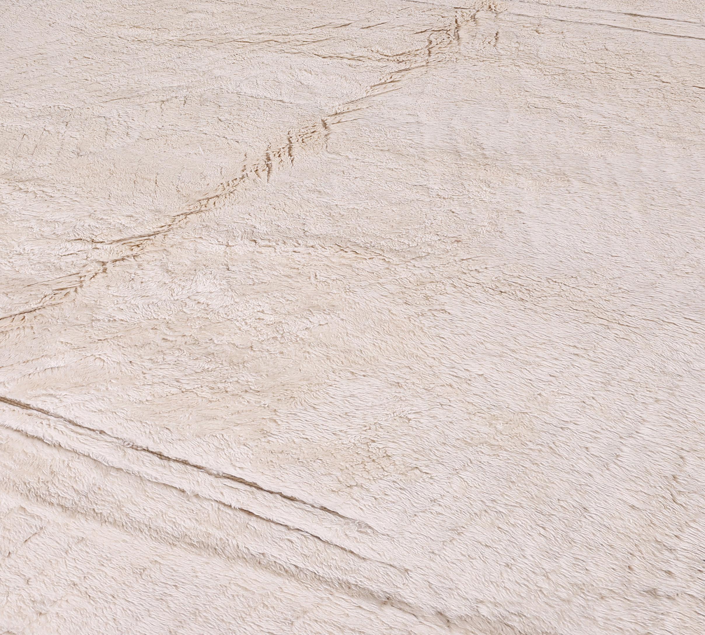Questo squisito tappeto marocchino Beni Ourain annodato a mano è un esempio senza tempo di artigianato nordafricano. Tessuto interamente in 100% lana naturale e non tinta color crema, il tappeto presenta un sottile motivo a griglia che unisce la
