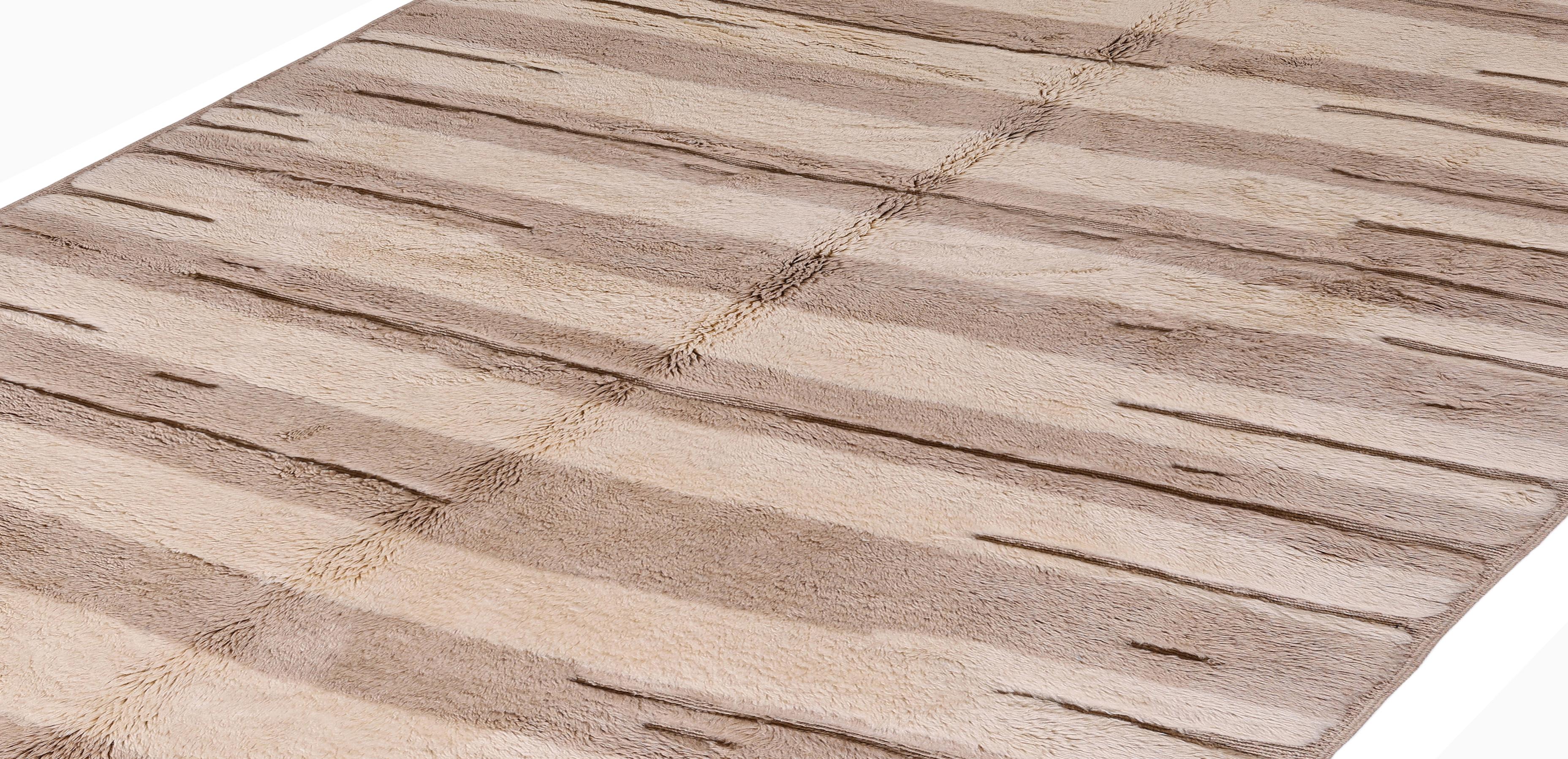 Esta alfombra marroquí contemporánea Beni Ourain combina la artesanía atemporal con la elegancia minimalista. Anudado a mano por artesanos bereberes con lana 100% natural, su suave y lujoso pelo y su sutil paleta neutra -con degradados de beige,