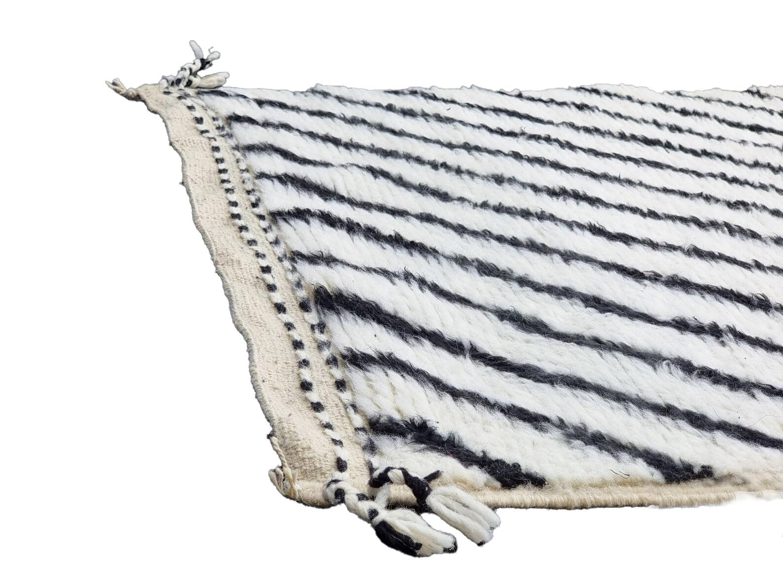 Moroccan Berber checkered and striped white and black wool runner rug. Handwoven by the north African Ben Ourian tribe. Black stripes set against a white background are associated with protection and balance in traditional Berber motifs. Hand woven