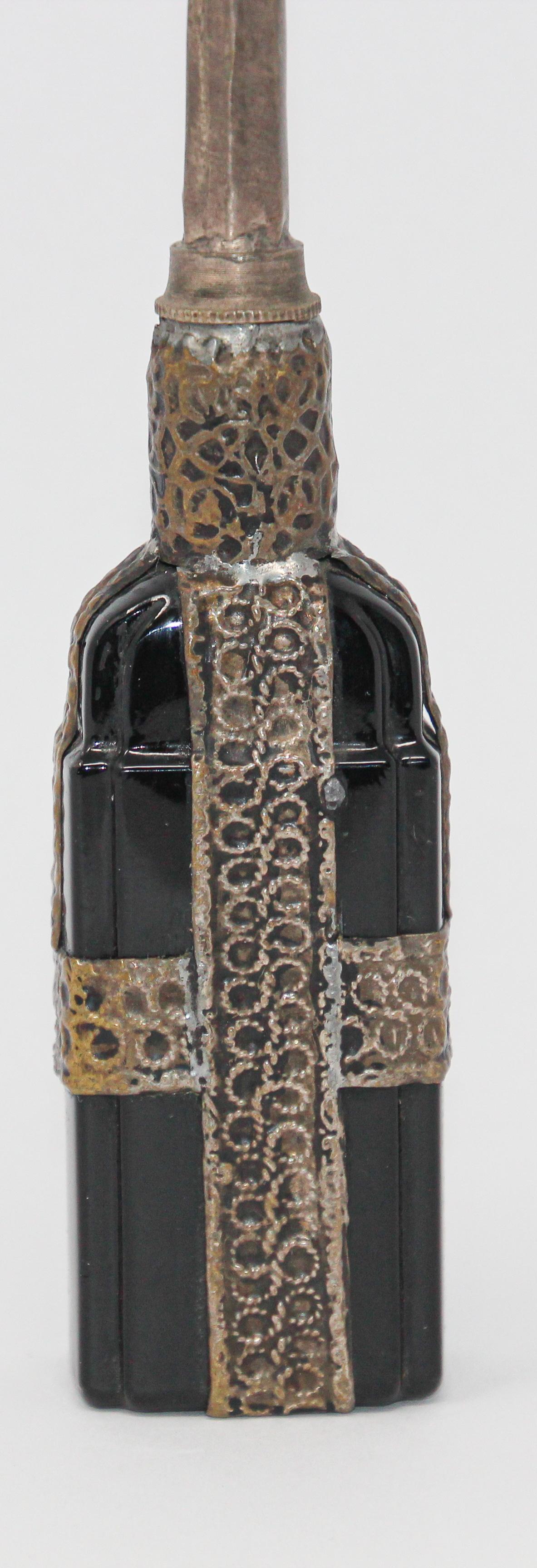 Handcrafted Moroccan Moorish glass perfume bottle or rose water sprinkler with raised embossed silvered metal floral design over black glass.
The pressed glass bottle in Art Deco, Art Nouveau style is oval shape with curved sides and hand decorated