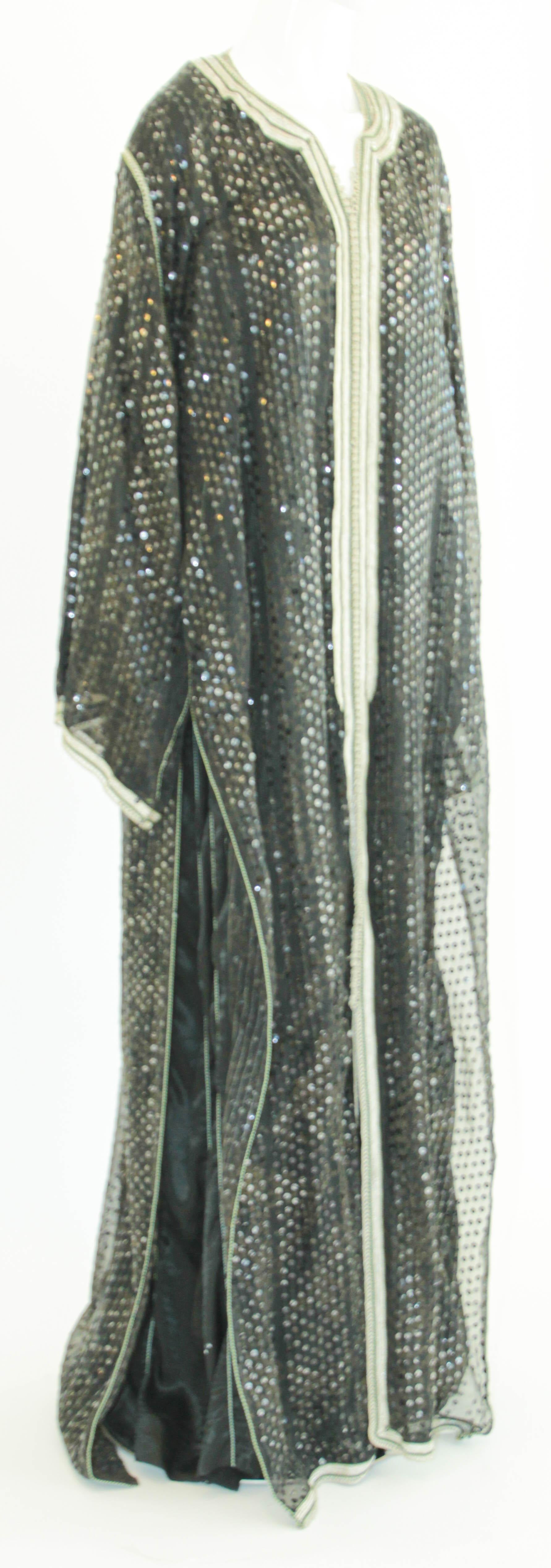 Elégant caftan marocain noir à paillettes avec bordure brodée argentée.
Il s'agit d'un ensemble de deux robes que vous pouvez porter ensemble ou séparément,
vers les années 1980.
Cette longue robe maxi set kaftan a un bord brodé d'argent et embelli