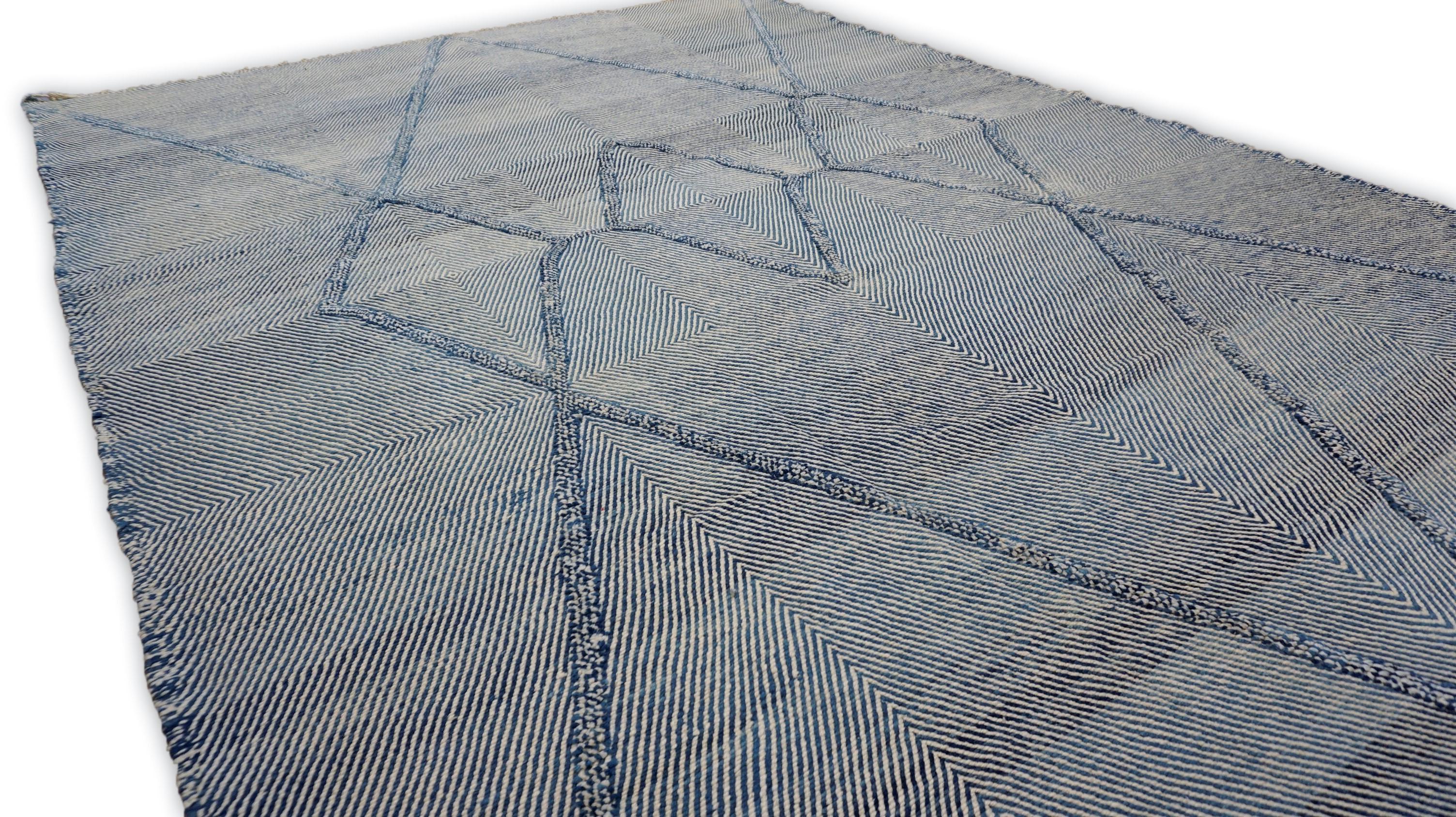 Esta asombrosa alfombra de lana anudada a mano muestra un diseño geométrico de rombos bellamente detallado en ricos tonos azules y marfil. Elaborada por expertos artesanos, la alfombra presenta diamantes a gran escala dibujados con precisión e
