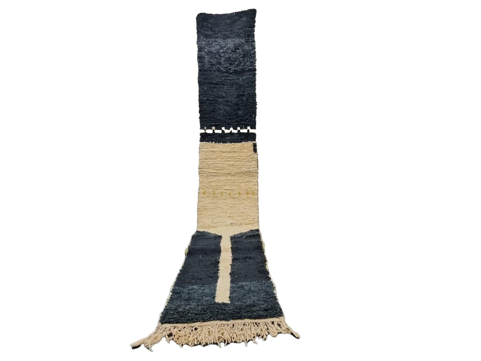 Tapis Boujad marocain tissé à la main en laine de mouton naturelle et douce, présentant des motifs géométriques noirs et beiges mêlant les cultures arabe et berbère du Maroc. Les couleurs sont fabriquées à partir de colorants naturels.

Largeur : 2
