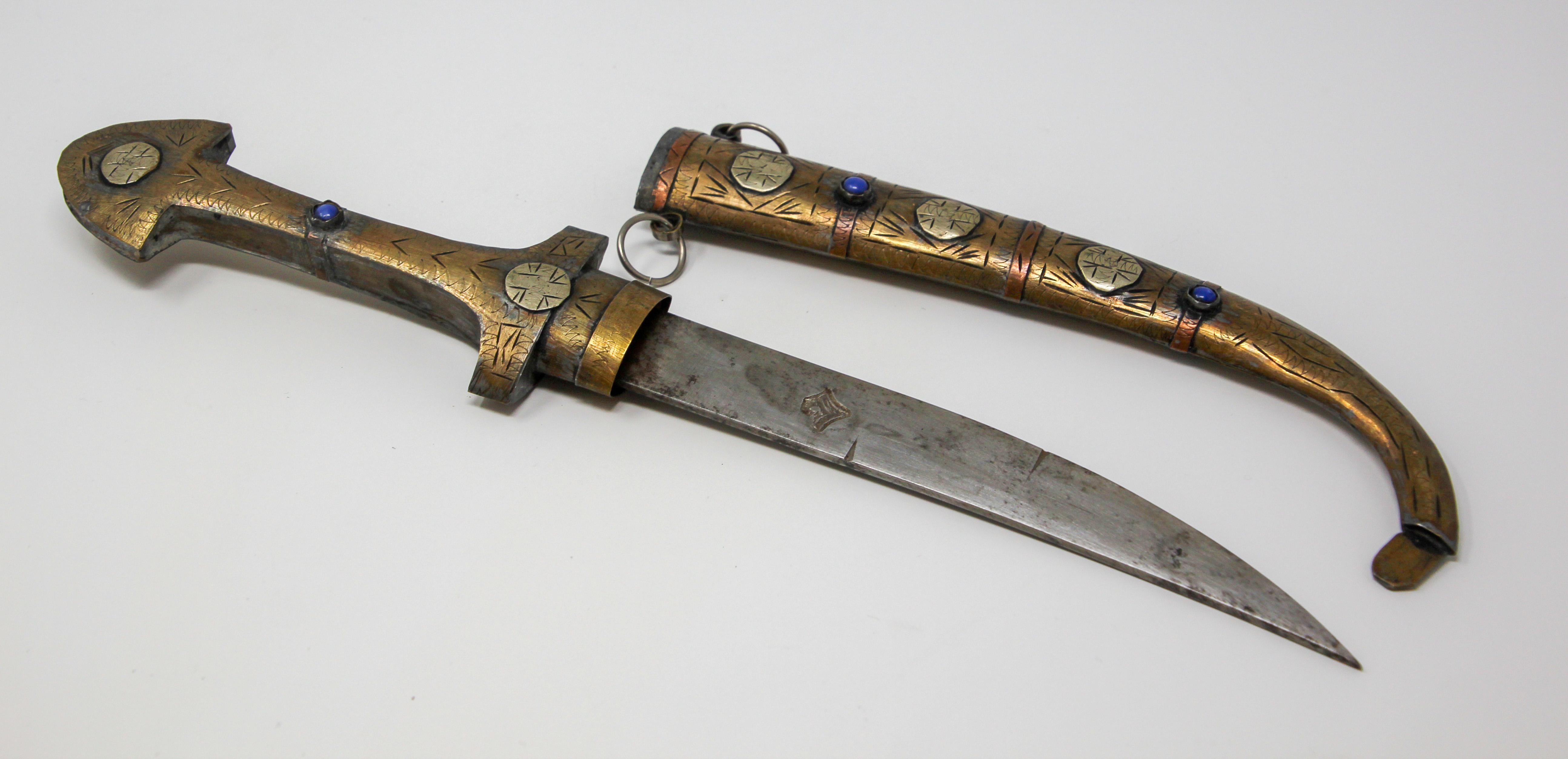 Handcrafted Moroccan brass dagger, mixed metal, copper, nickel and enamel.
Moroccan Hand carved Khoumiya dagger, of typical shape with curved blade, with brass fittings, complete with scabbard with tribal Berber motifs. 
Handcrafted by artisans in