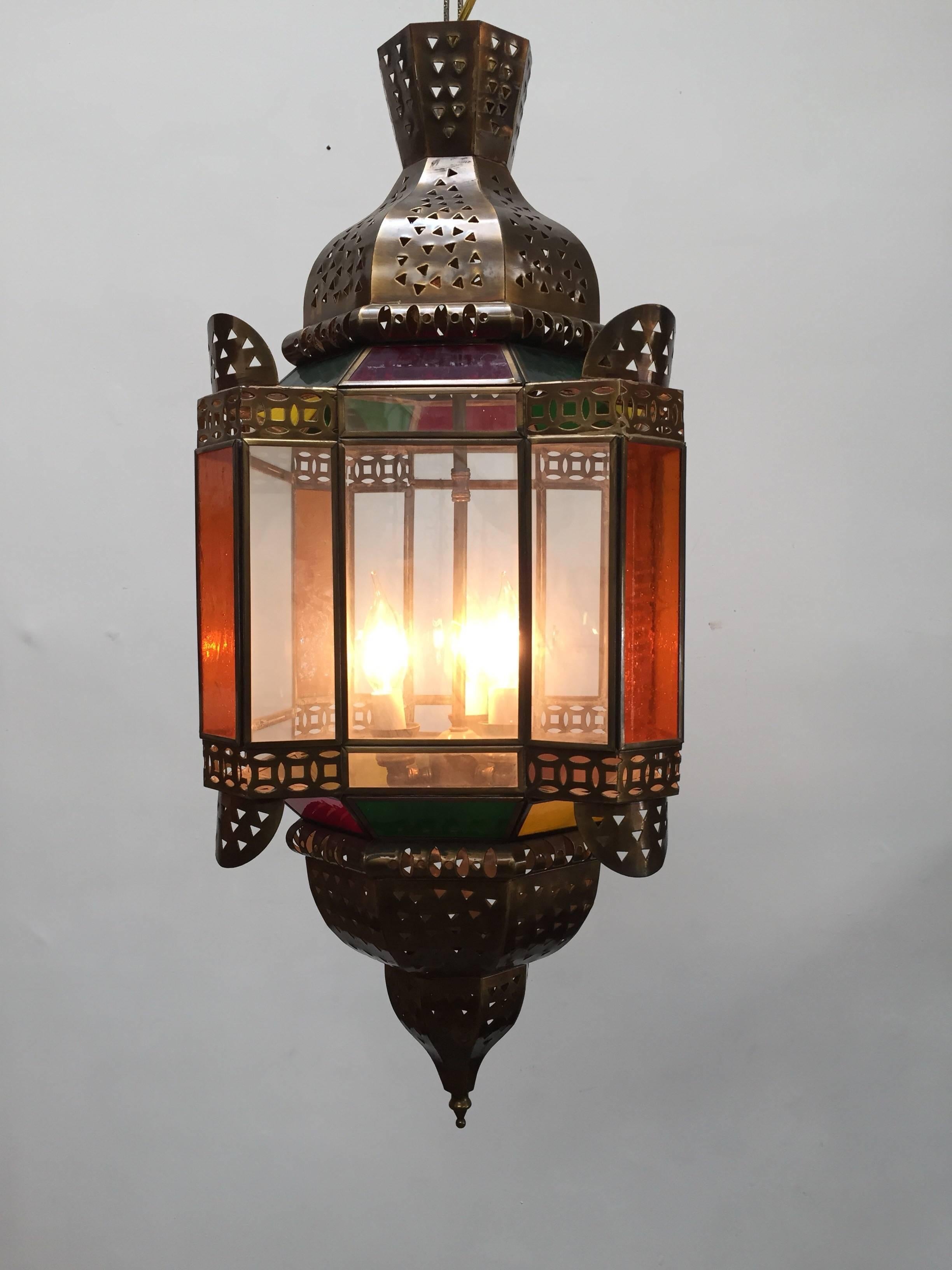 Handcrafted Moroccan light fixture with clear and colored glass.
Moorish style glass pendant with colored glass in green, red, yellow and amber with filigree brass openwork metal design.
This Moroccan light fixture is rewired for three lights.