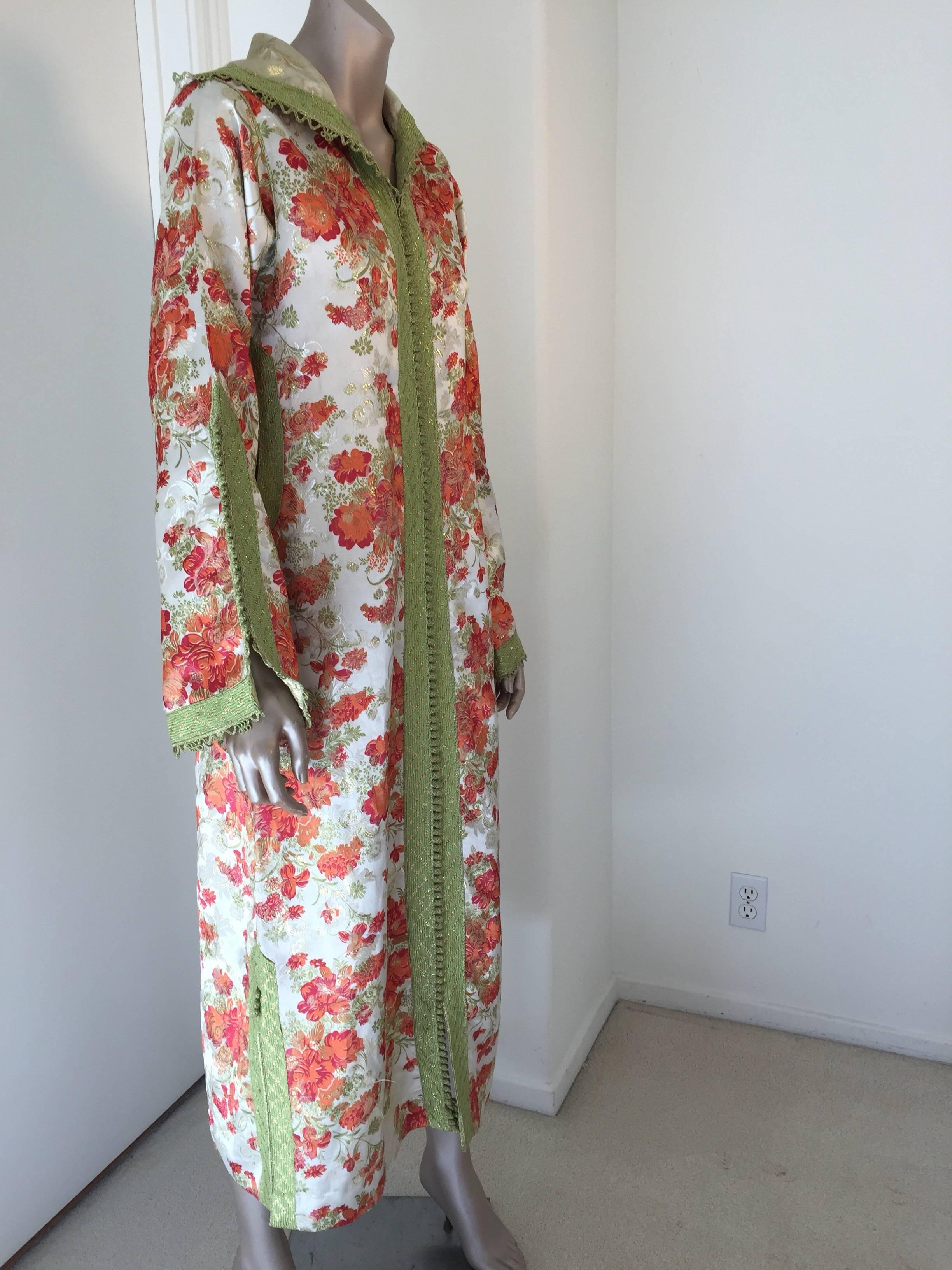 Elegant vintage designer Moroccan kaftan, hooded caftan white with red and gold flowers and embroidered with green woven braided buttons and loops.
This chic Gypsy Bohemian multi-color maxi dress hooded kaftan is embellished with green woven buttons