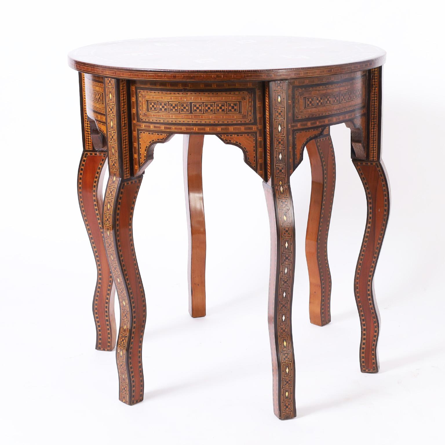 Impressive antique Moroccan round table crafted in walnut with a dazzling display of inlaid marquetry on the top using mother of pearl, bone, ebony, kingwood, mahogany, and teak in elaborate geometric designs over a base with inlaid marquetry skirts