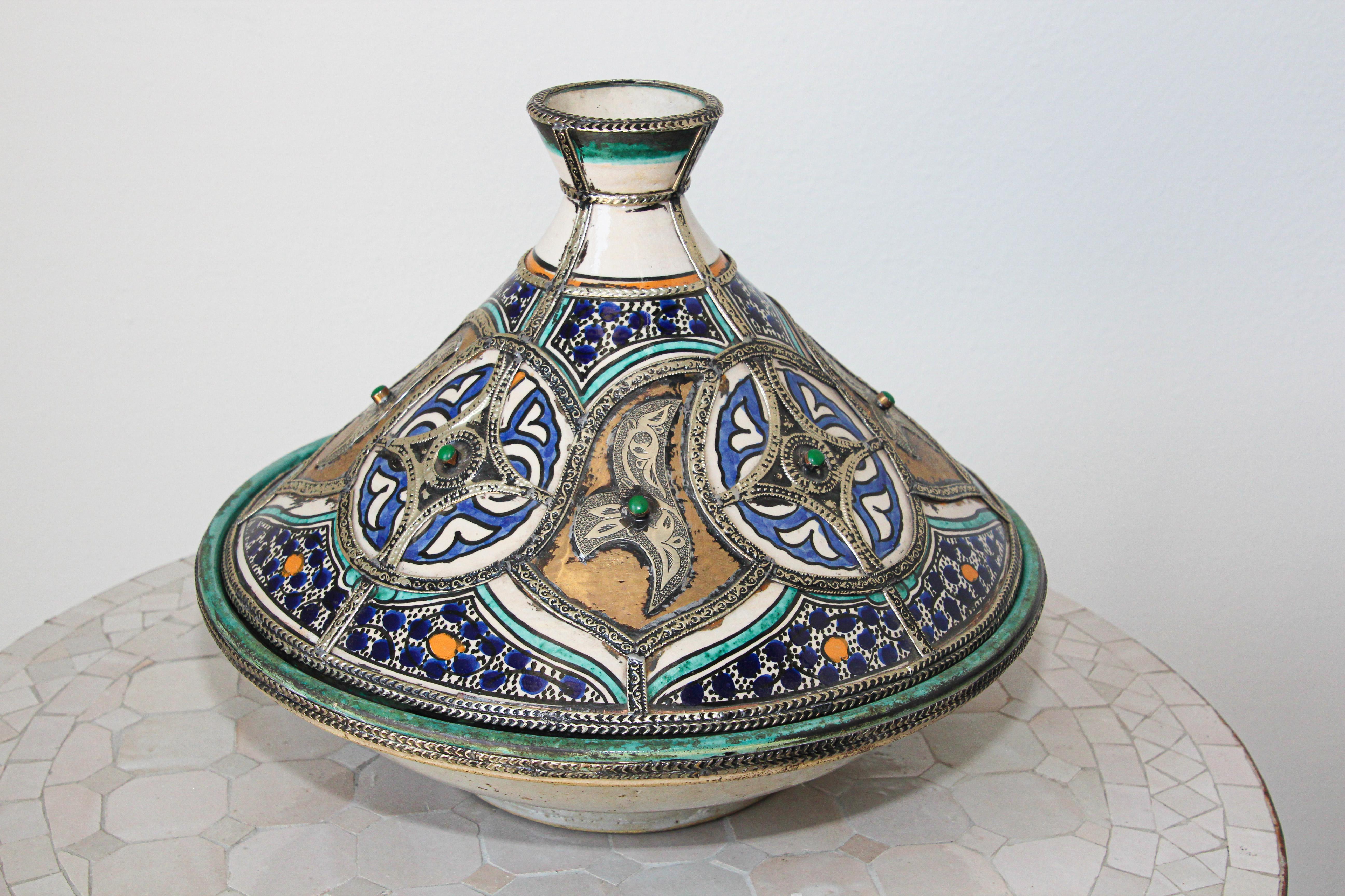 Moroccan large ceramic decorative serving bowl tajine polychrome with leather, stones and metal overlay with conical overlay lid.
The bottom is a circular ceramic bowl and the top of the tagine is distinctively shaped into a cone.
Handcrafted and