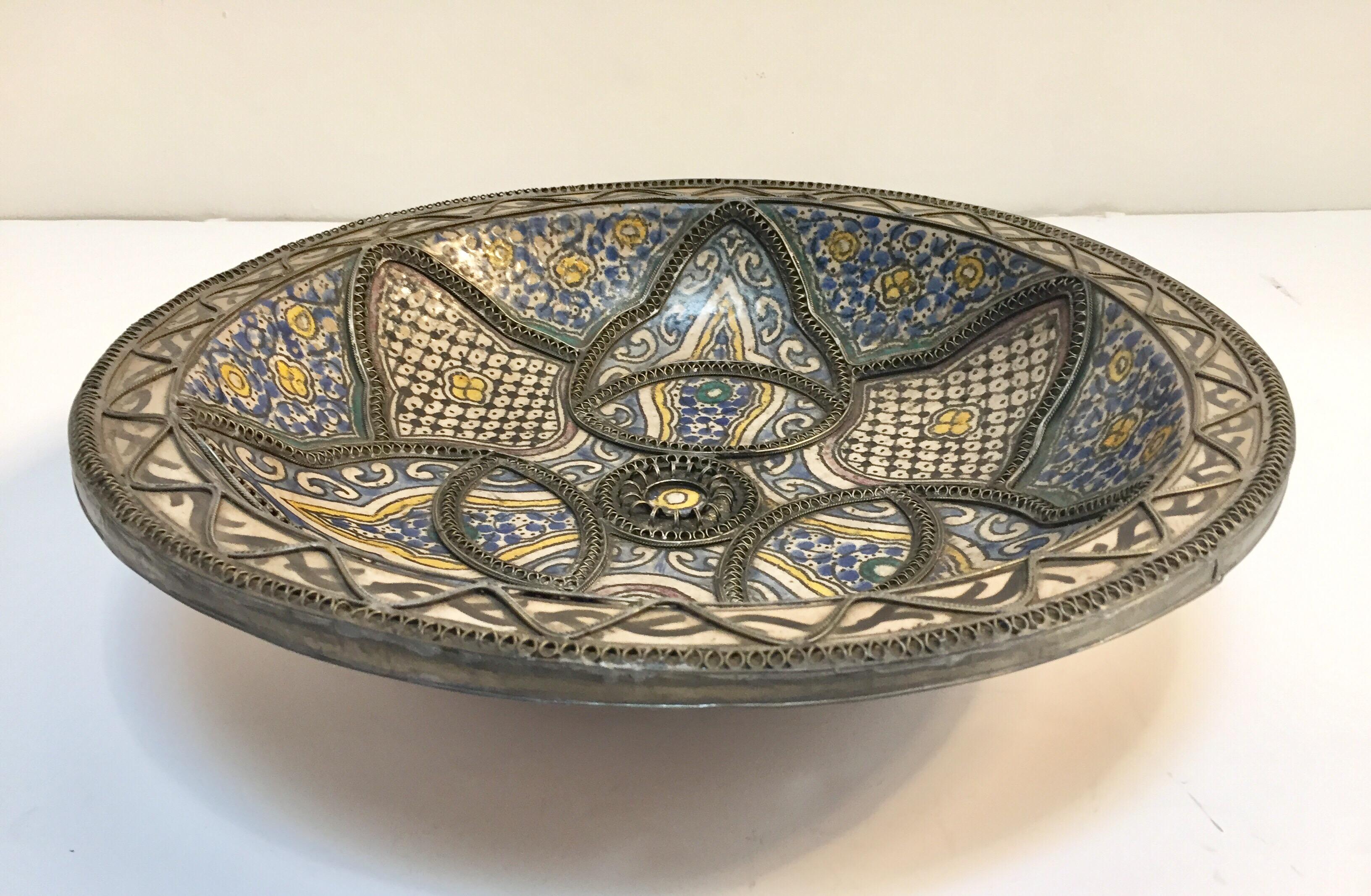 Handcrafted antique large Moroccan polychrome decorative ceramic plate from Fez. Bleu de Fez, very nice designs hand painted by artist in Fez.
Geometrical and floral designs and adorned with nickel silver filigree designs.