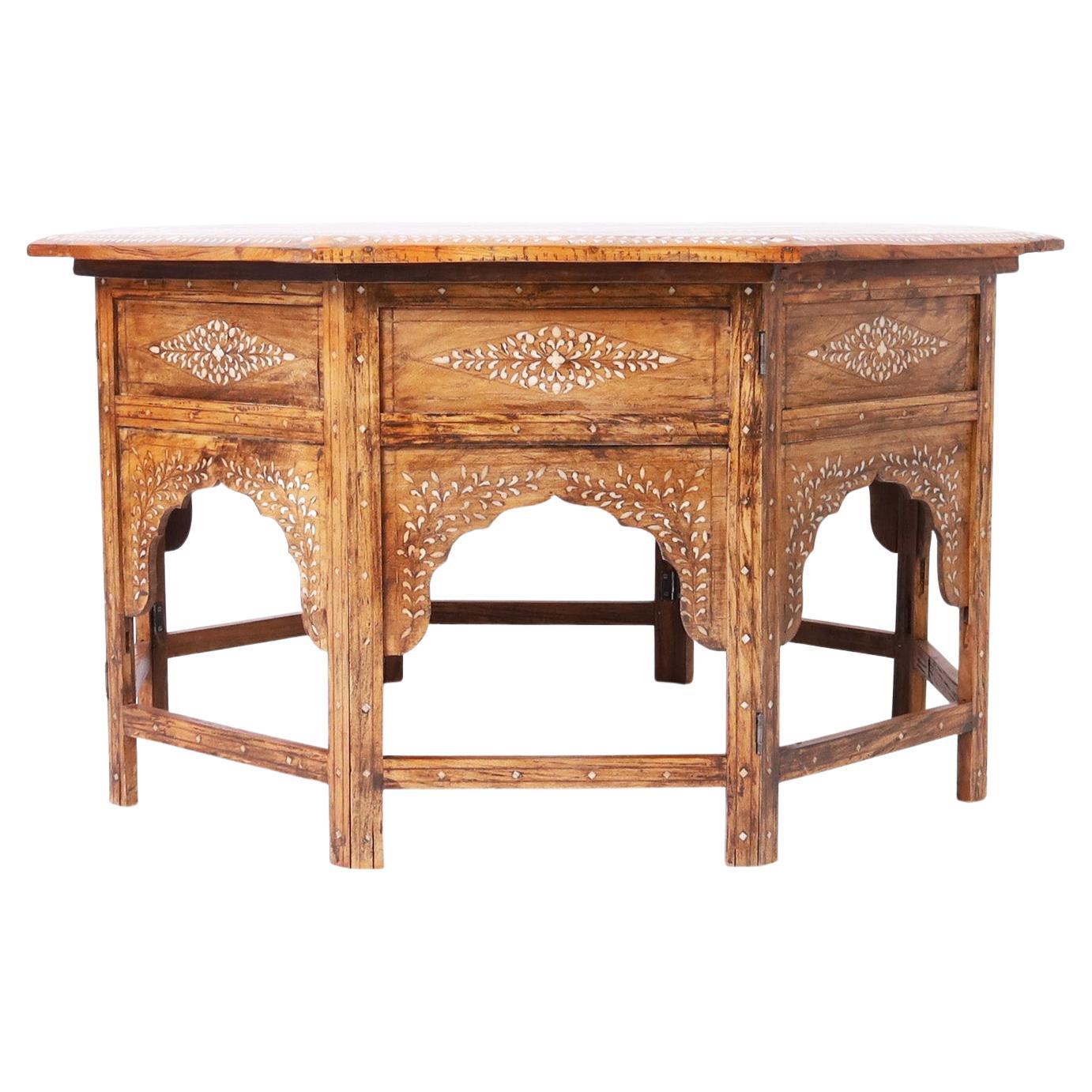 Impressive antique Moroccan coffee table crafted with walnut in an octagon form with elaborate graceful floral bone inlays on the top over a base with architecturally interesting arches between eight legs.