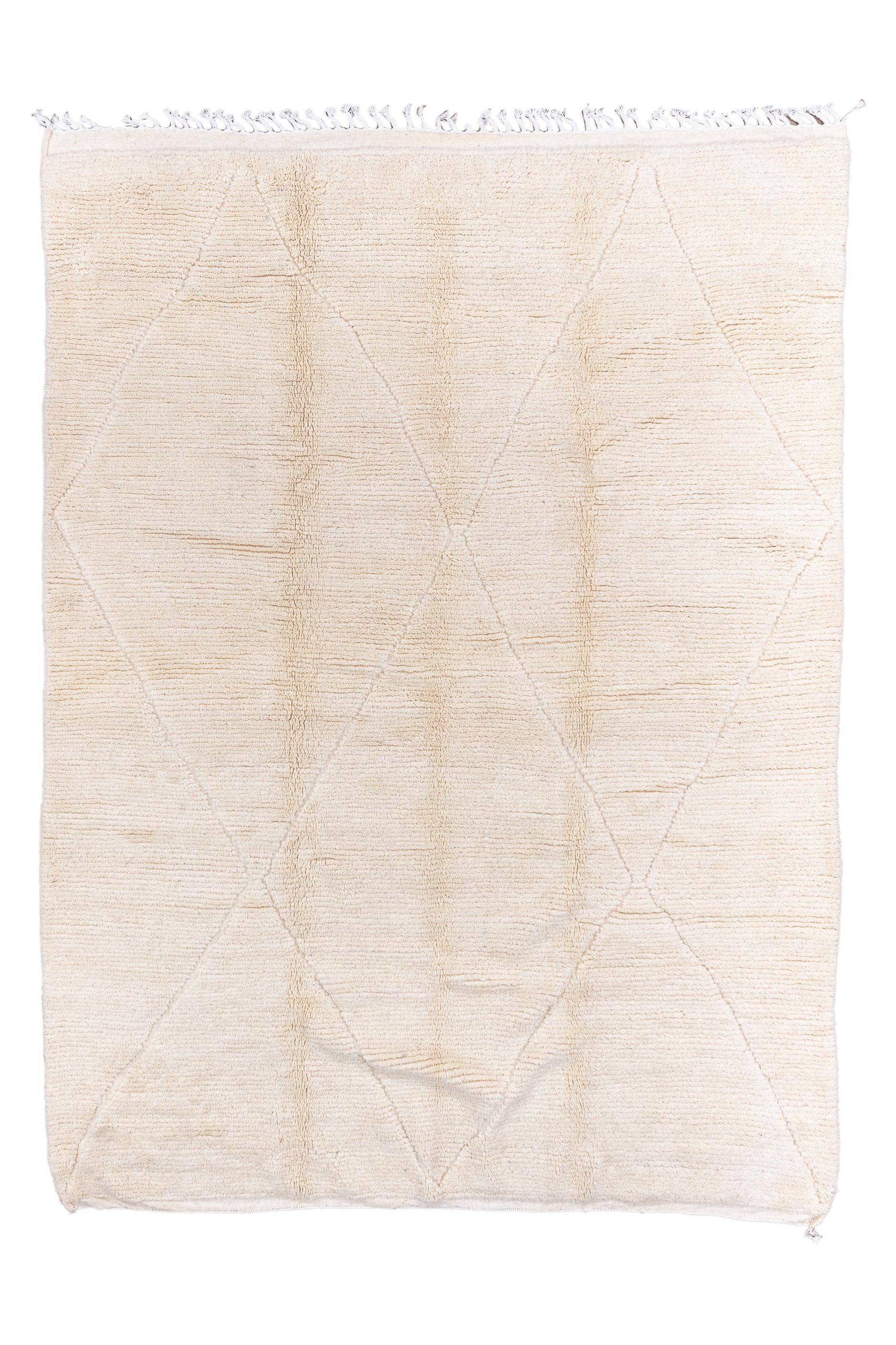 Il più vicino al monocromatico che si possa ottenere, ma con un motivo a losanghe molto discreto su un fondo di sabbia naturale. Senza confini, quindi. Fascia di nappe strette all'estremità superiore. Vello alto e trama rustica e grossolana. Come