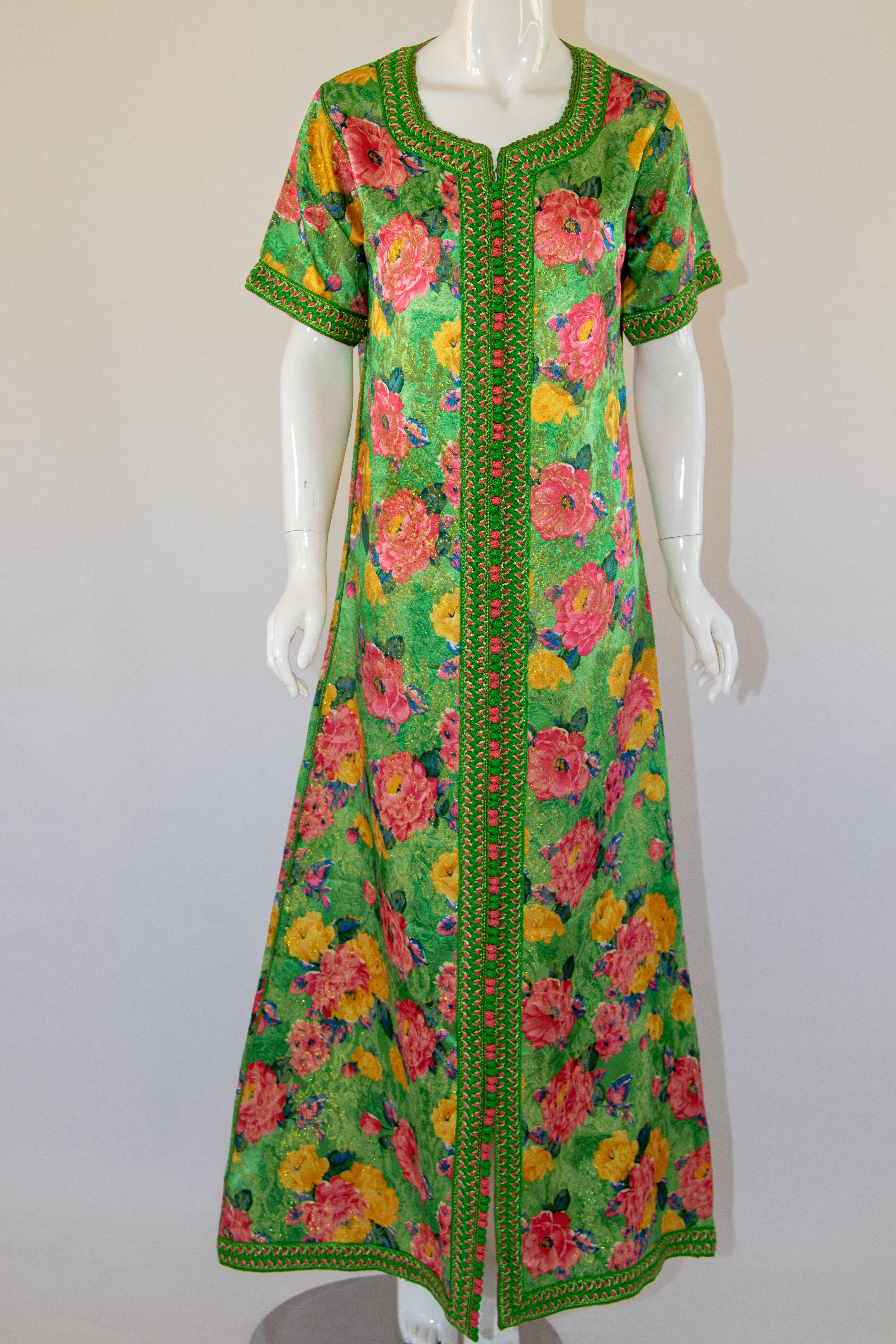 Moroccan exotic floral green caftan gown, circa 1970s.
The front of this caftan is embellished with woven green and pink buttons and loops that run down the centre to the hemline.
Short sleeves great for hot summer vacation, great large flowers in
