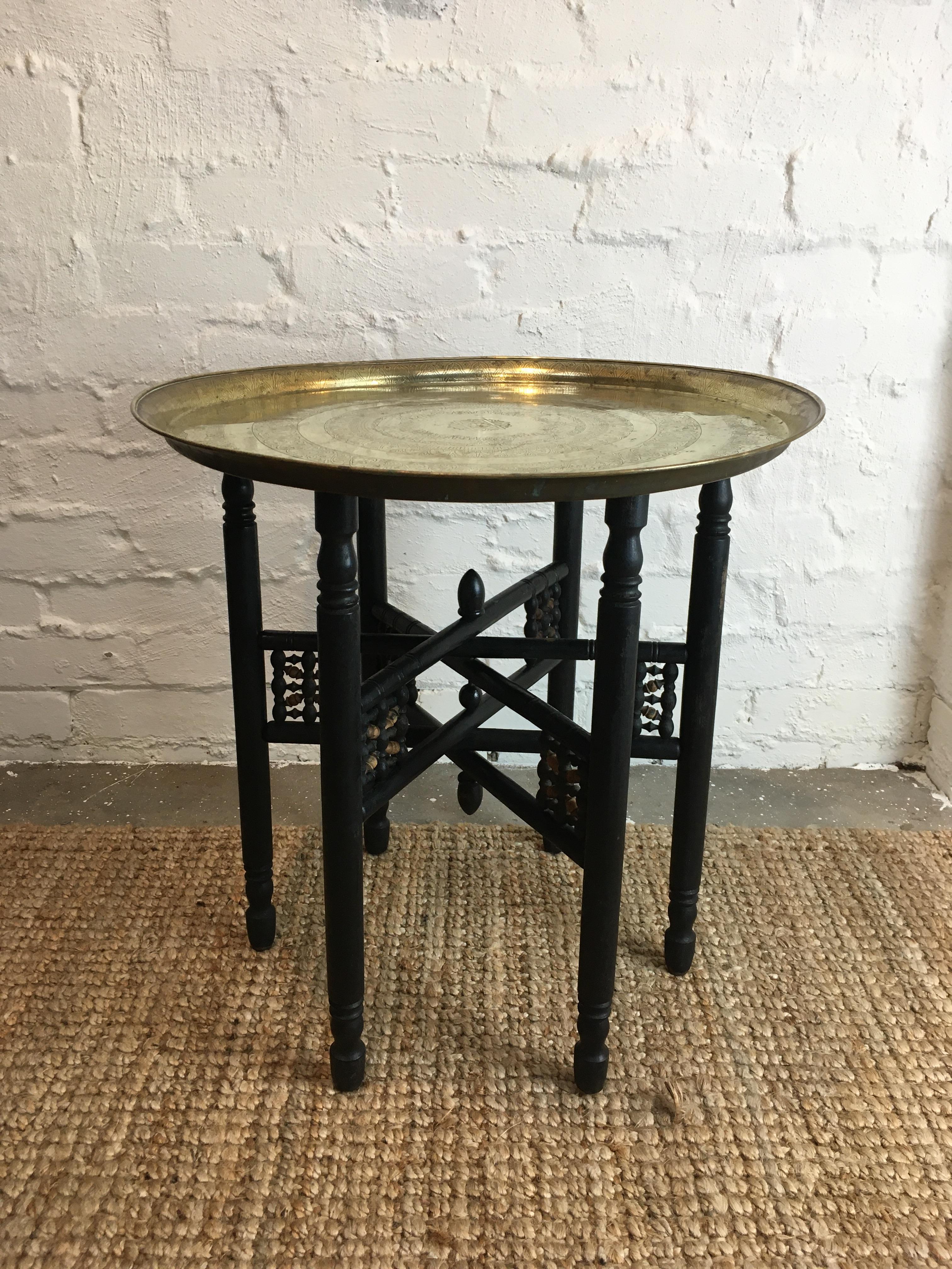 An early 20th century Moroccan brass coffee or side tray table with folding ebonised turned timber base. 

The brass tray depicts cattle, sheep, goats and elephants in two bands, with several bands of stylised fig vines and date palms. In the