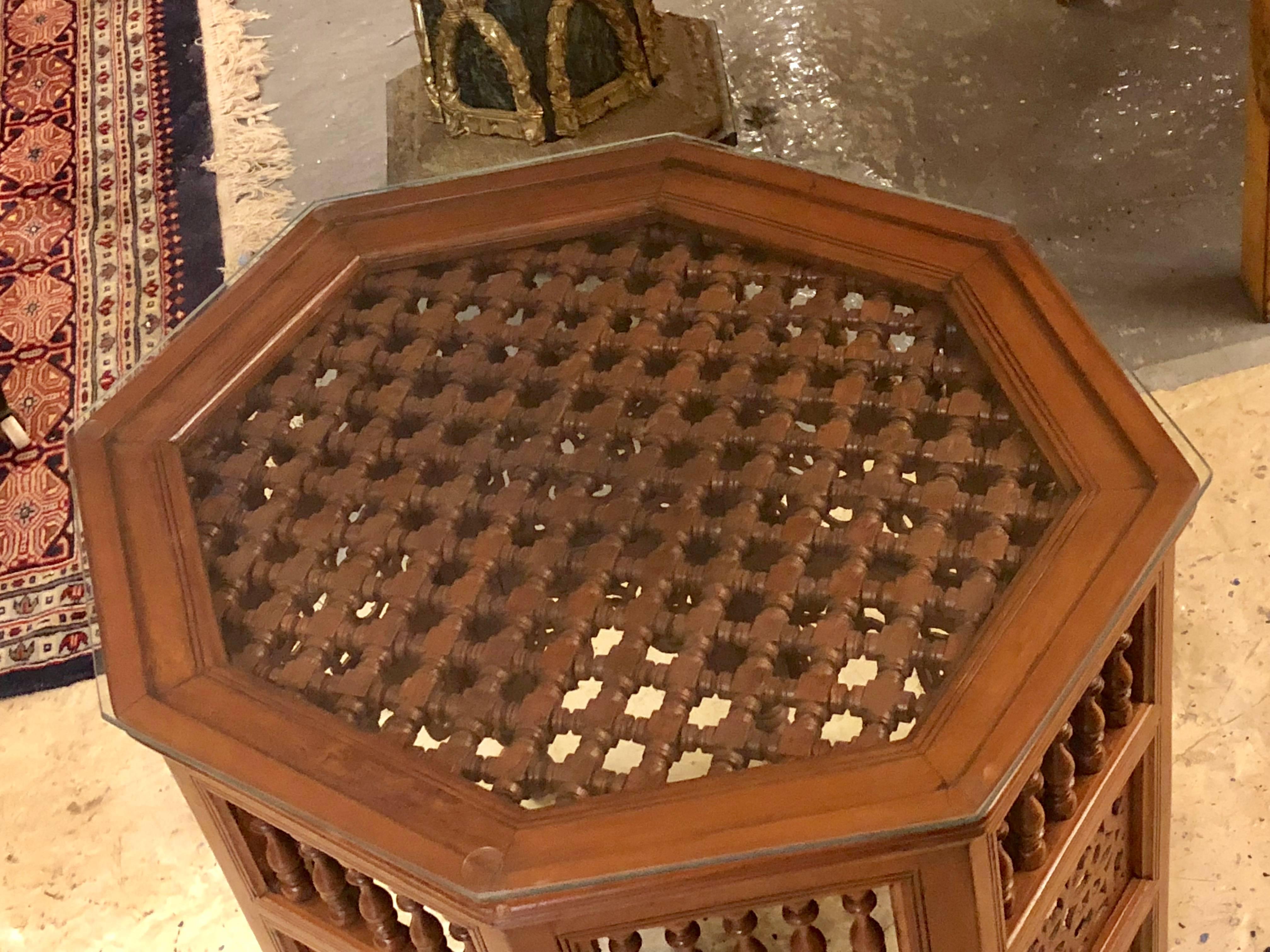 Moroccan glass top carved wood end or side table. This simply stunning end table sports an inset glass top with a faux bamboo wooden design. The solid wood construction is reminiscent of old world charm and workmanship. This piece is part of a large