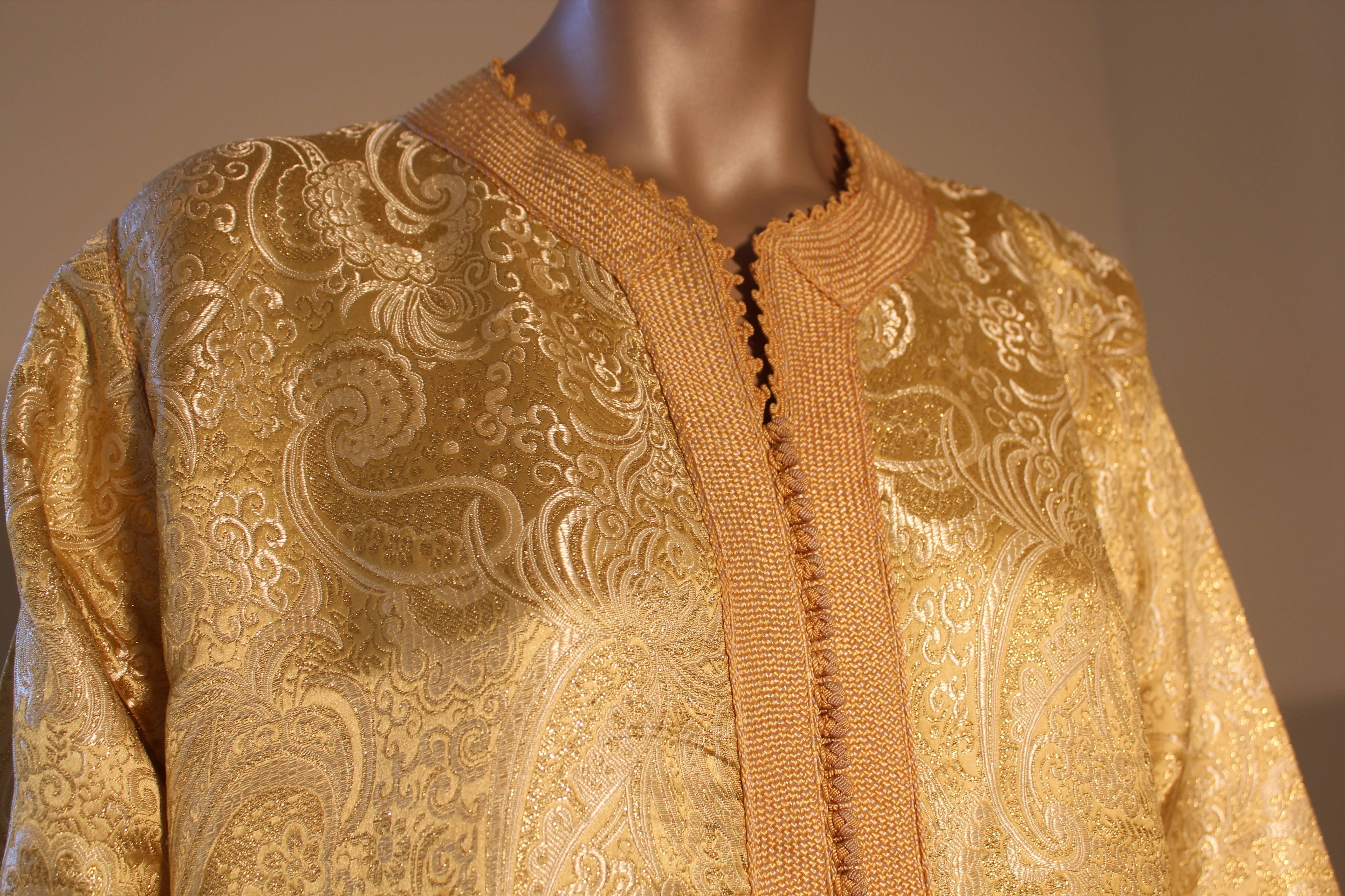Moroccan vintage exotic gold brocade caftan gown, circa 1970s.
The luxurious kaftan is designed with brilliant gold metallic fabric.
The front of the elegant Kaftan gown is embellished at the front with woven gold buttons and loops that run down the