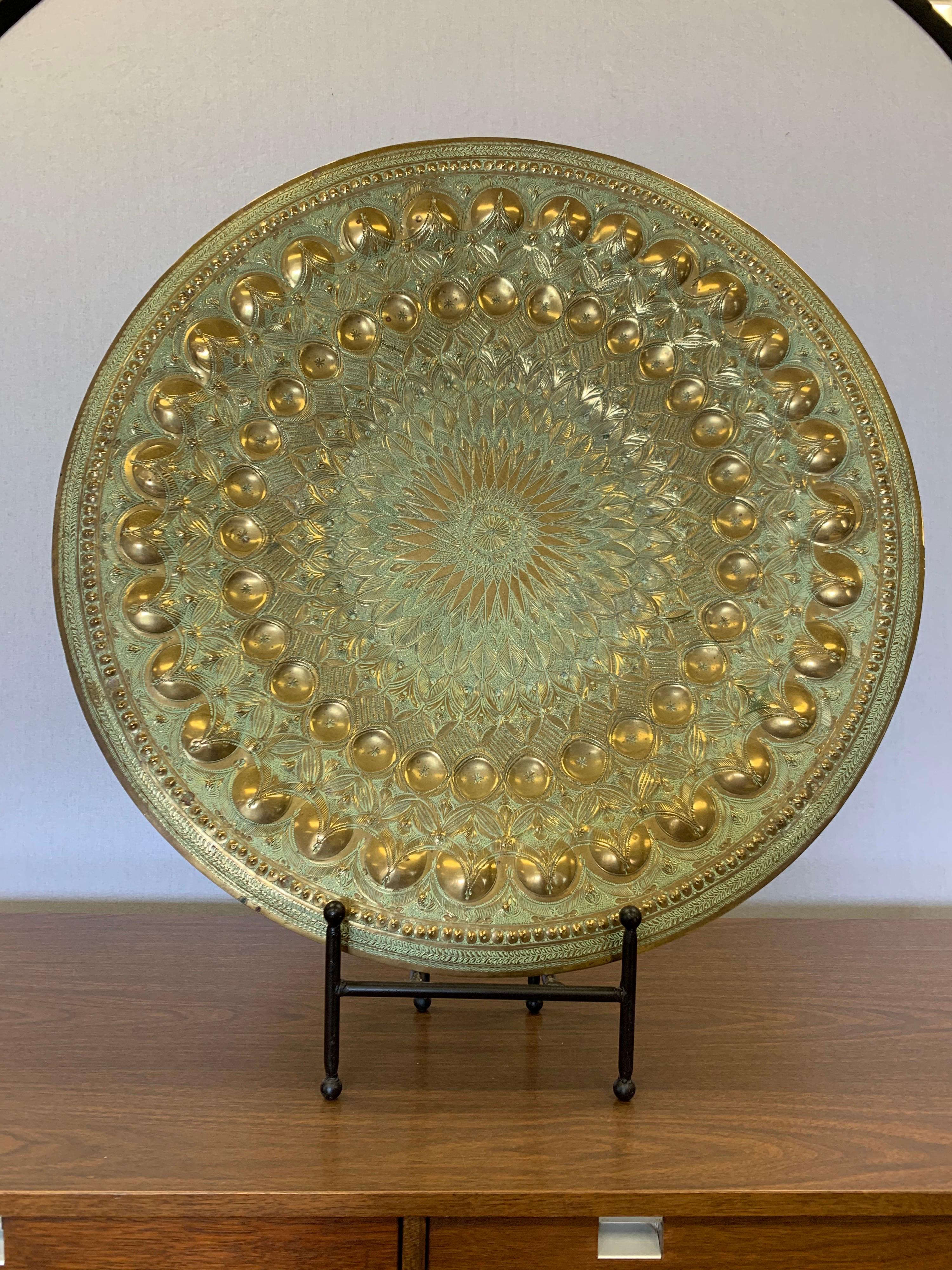 Moorish hammered round brass plaque with a pattern of engraved and embossed circles and feathers. Color is brass with seafoam green.
