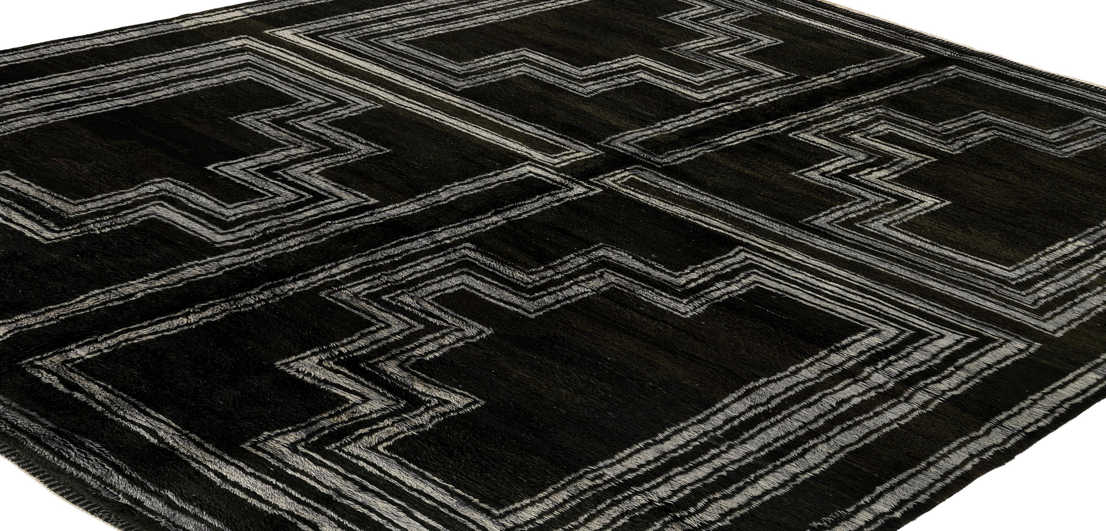 Bold and graphic, this Moroccan hand-knotted wool rug features a dramatic black field with intricate ivory geometric lines that form a maze-like symmetrical pattern. The design is divided into four quadrants, each echoing stepped motifs reminiscent
