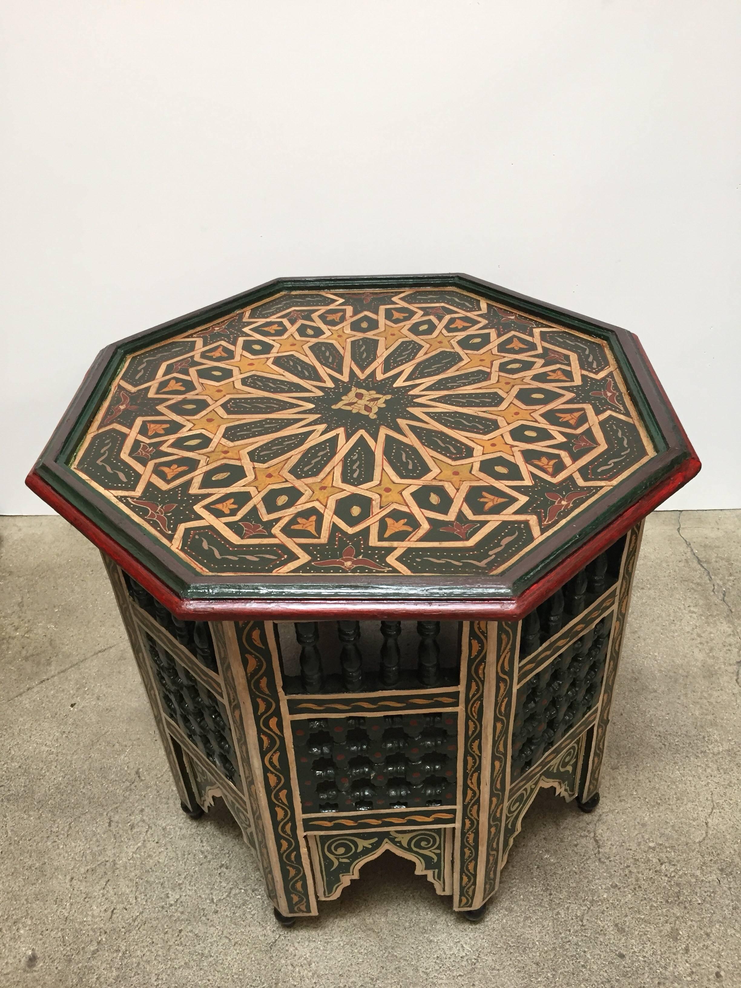Moroccan colorful hand-painted dark green side table with Moorish design and open fret mousharabie work on sides.
Dark green background with multicolored floral top and geometric designs.
Very fine wood artwork on an octagonal shape with Moorish