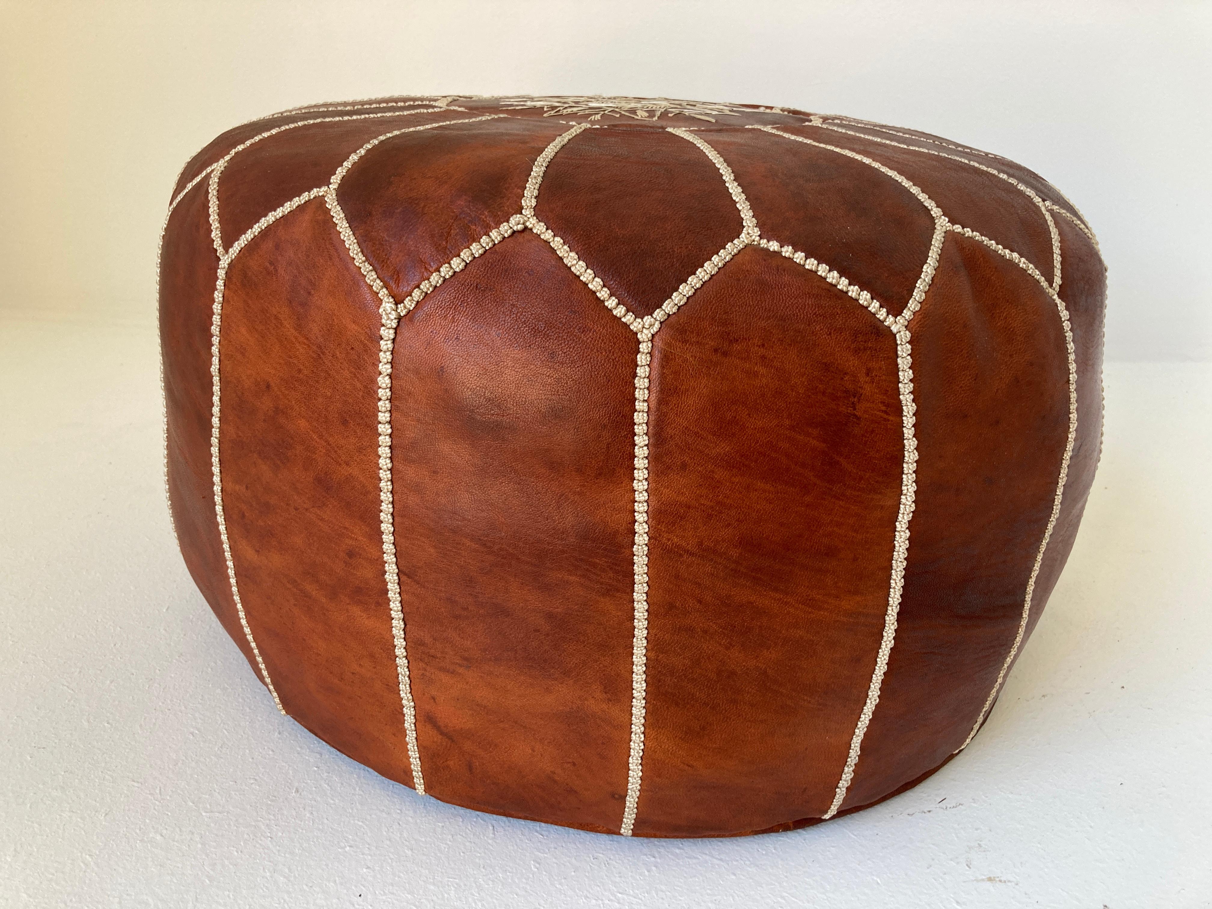 Moroccan handcrafted brown camel leather ottoman, with embroideries.
Cod be used a foot sto, or side table or ottoman.
The Moroccan leather poufs are hand-toed and embroidered with white tread.
Very nice handmade vintage Moroccan tan camel cor