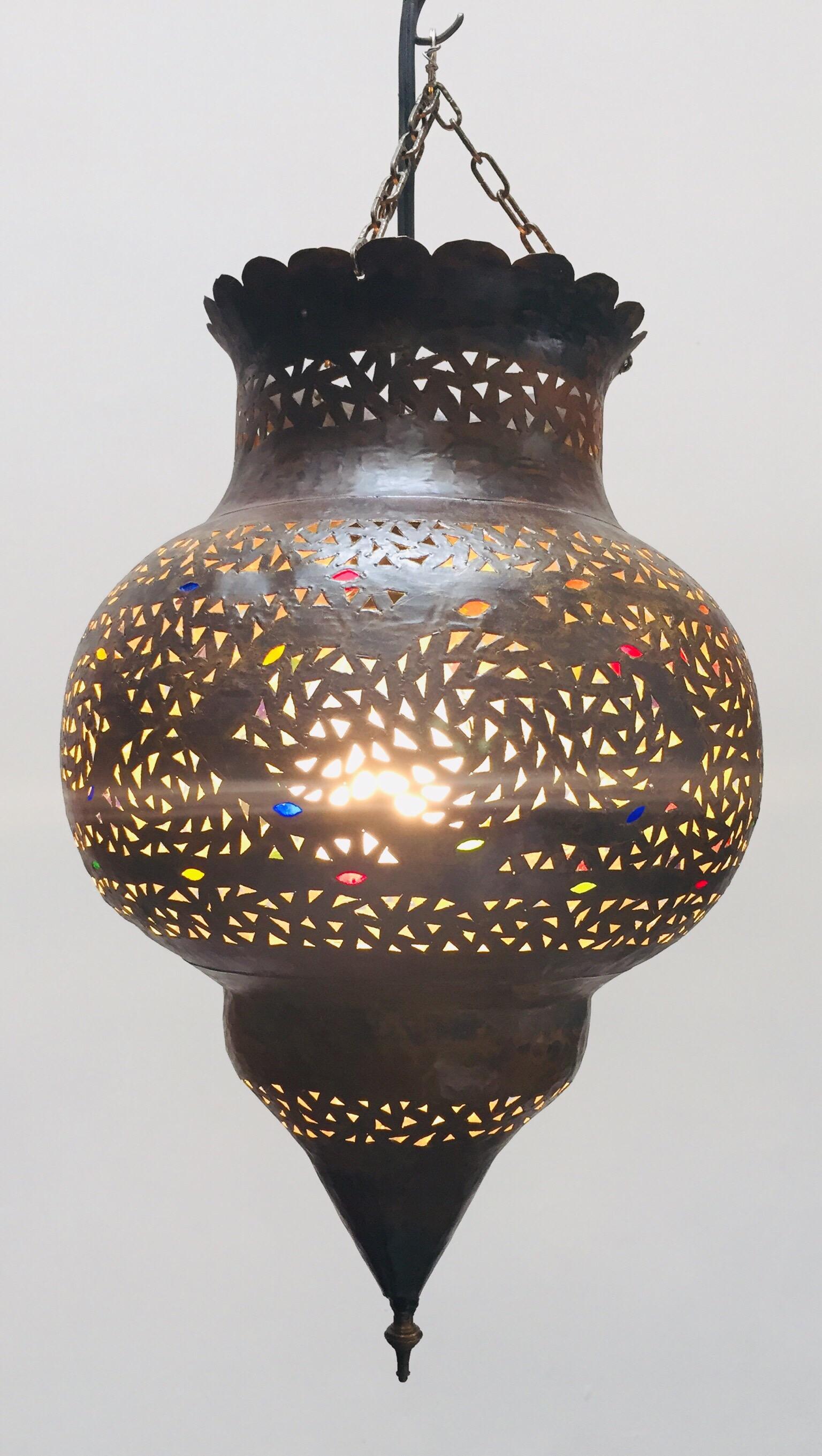 Stylish handcrafted Moroccan lantern pendant with multi-color molded glass and metal with an antique bronze finish.
Handmade with small cut-glass with Moorish filigree open metal work Moorish design.
Comes with a black cord for one light bulb,