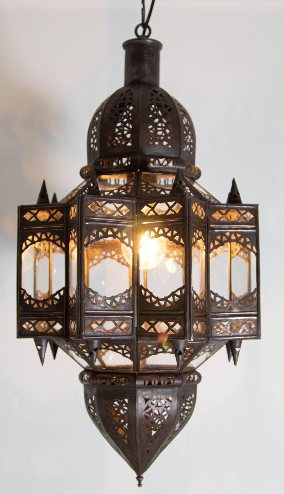 Vintage Moroccan Moorish star shape in clear glass and metal lantern.
Clear Glass star shape lantern pendant handcrafted by Moroccan skilled artisans in Marrakech.
The metal is hand-cut in floral and geometric Moorish Islamic designs.
The lantern is