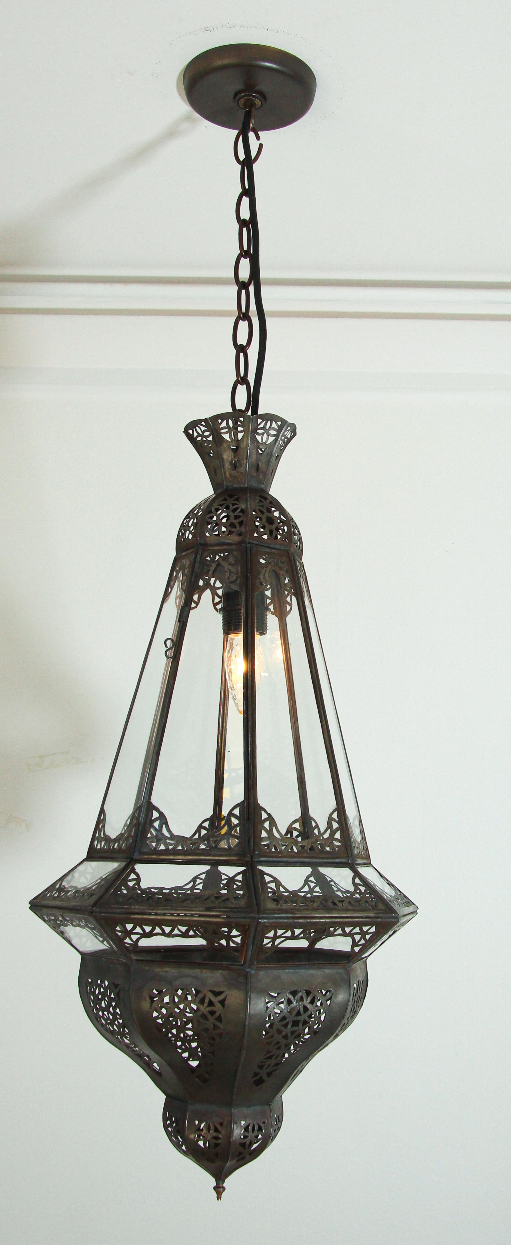 Moroccan lantern in diamond shape with clear glass and metal.
This Moorish light fixture is handcrafted by artisans in Morocco
The metal is delicately hand-cut in filigree Moorish designs, brass finial.
The vintage Moroccan Harem lantern is