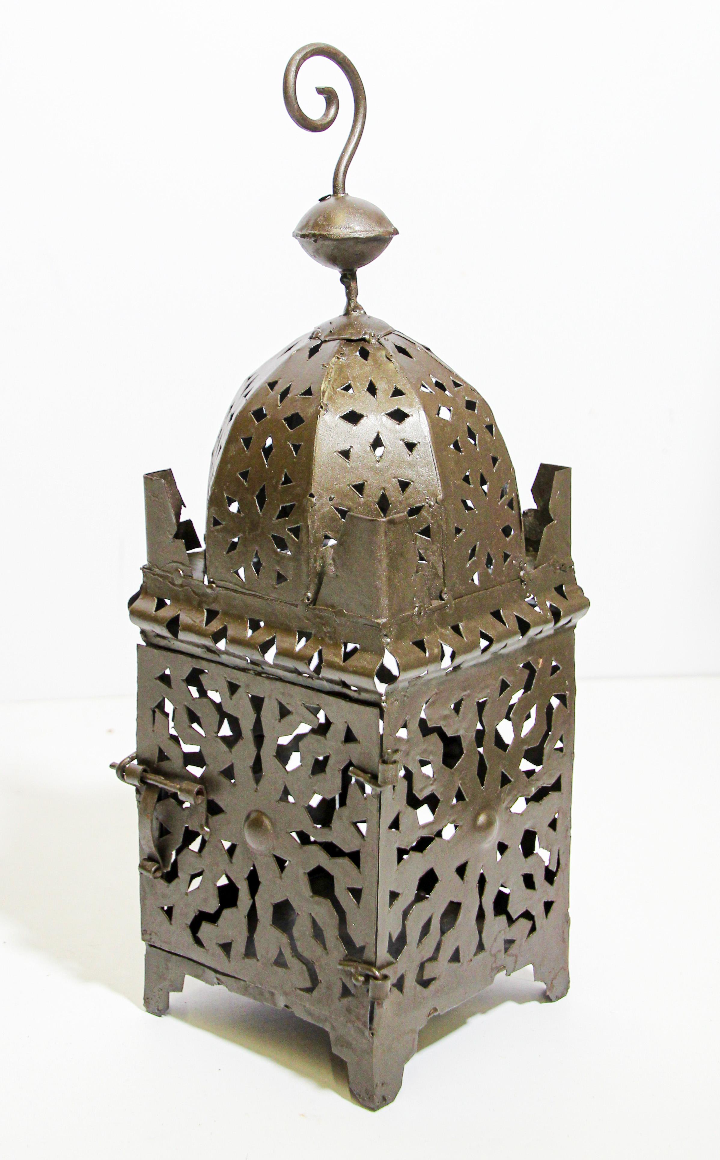 Moroccan Moorish metal candle lantern with open metal work Moorish design.
Hurricane candle lamp handcrafted in Morocco by artisans, metal handcut and hammered with Moorish design, open in front for use with pillar candles.
The lantern has a small