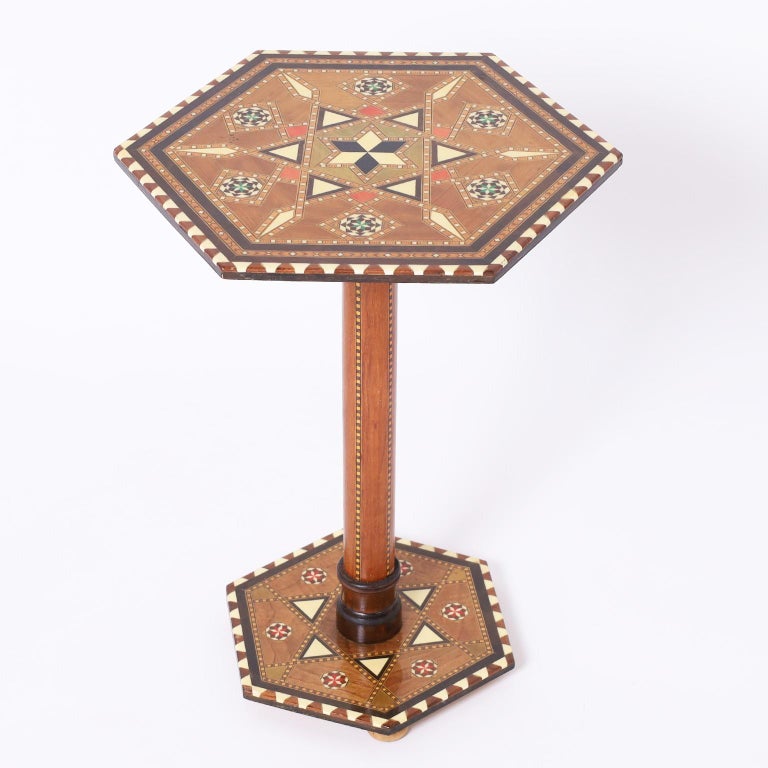 Standout Moroccan table or stand crafted in walnut with a hexagon top featuring exotic inlays including bone, ebony and mahogany over a simple round pedestal on an inlaid hexagon base.