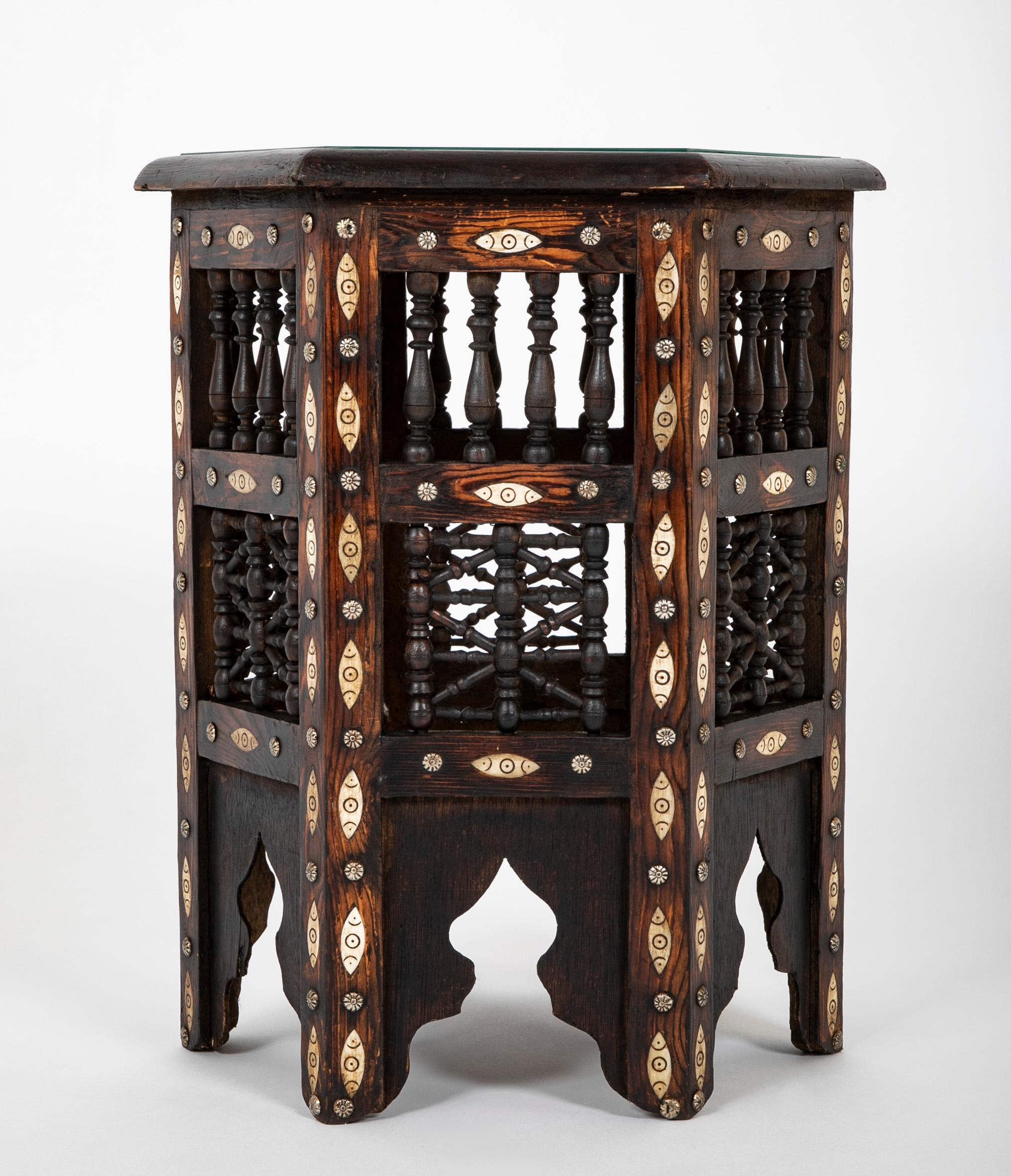 Moroccan six sided glass topped side table with incised bone inlay and nail heads, and signature decorative turned wood spindles throughout. Rich and warm patina, a very handsome side, end or drinks table. New, scratch free glass top. This Moorish