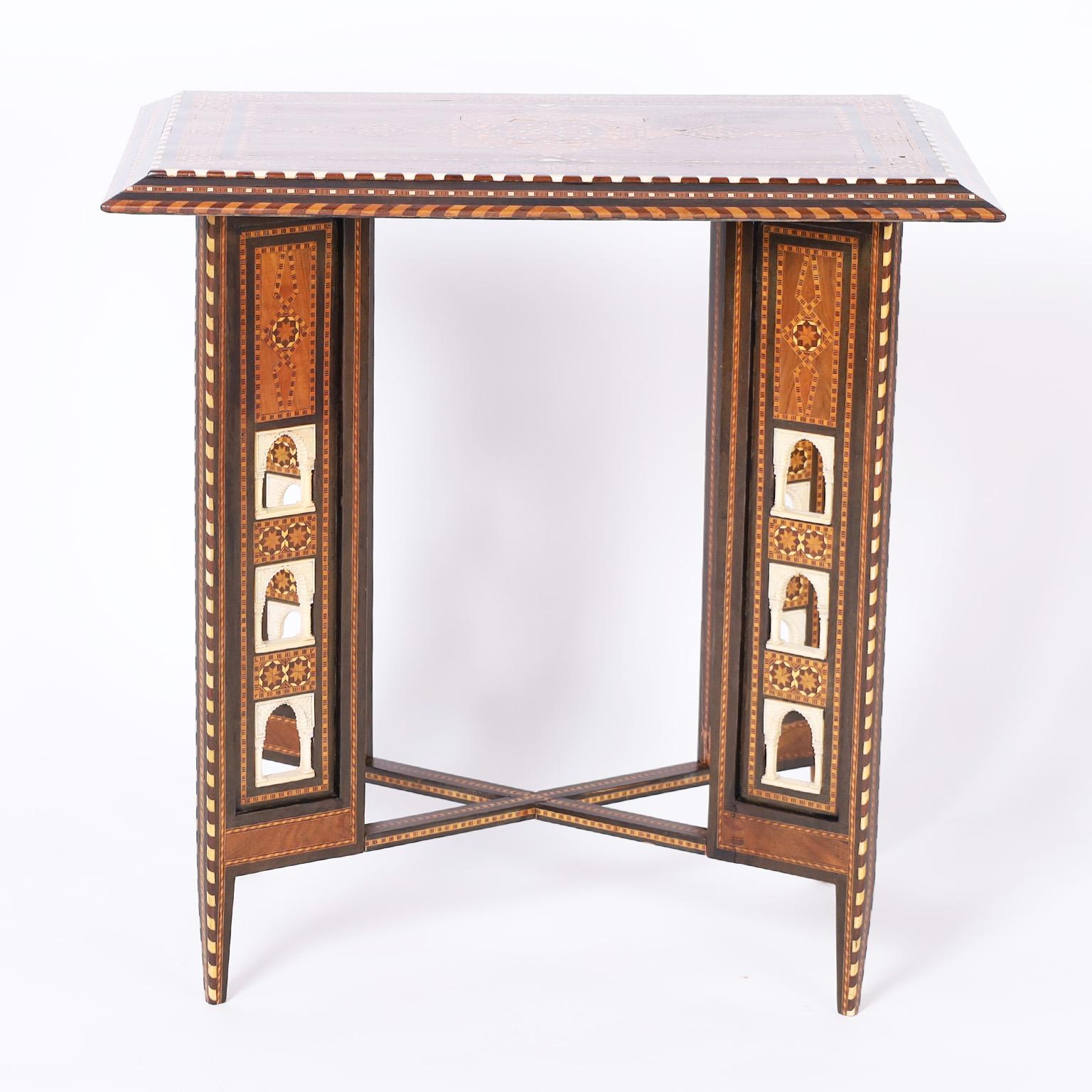 Near Eastern antique table or stand crafted in walnut featuring a rectangular top inlaid with geometric designs using bone and exotic hardwoods. The base has an unusual X form with geometric inlays and carved bone moorish arches over tapered legs.