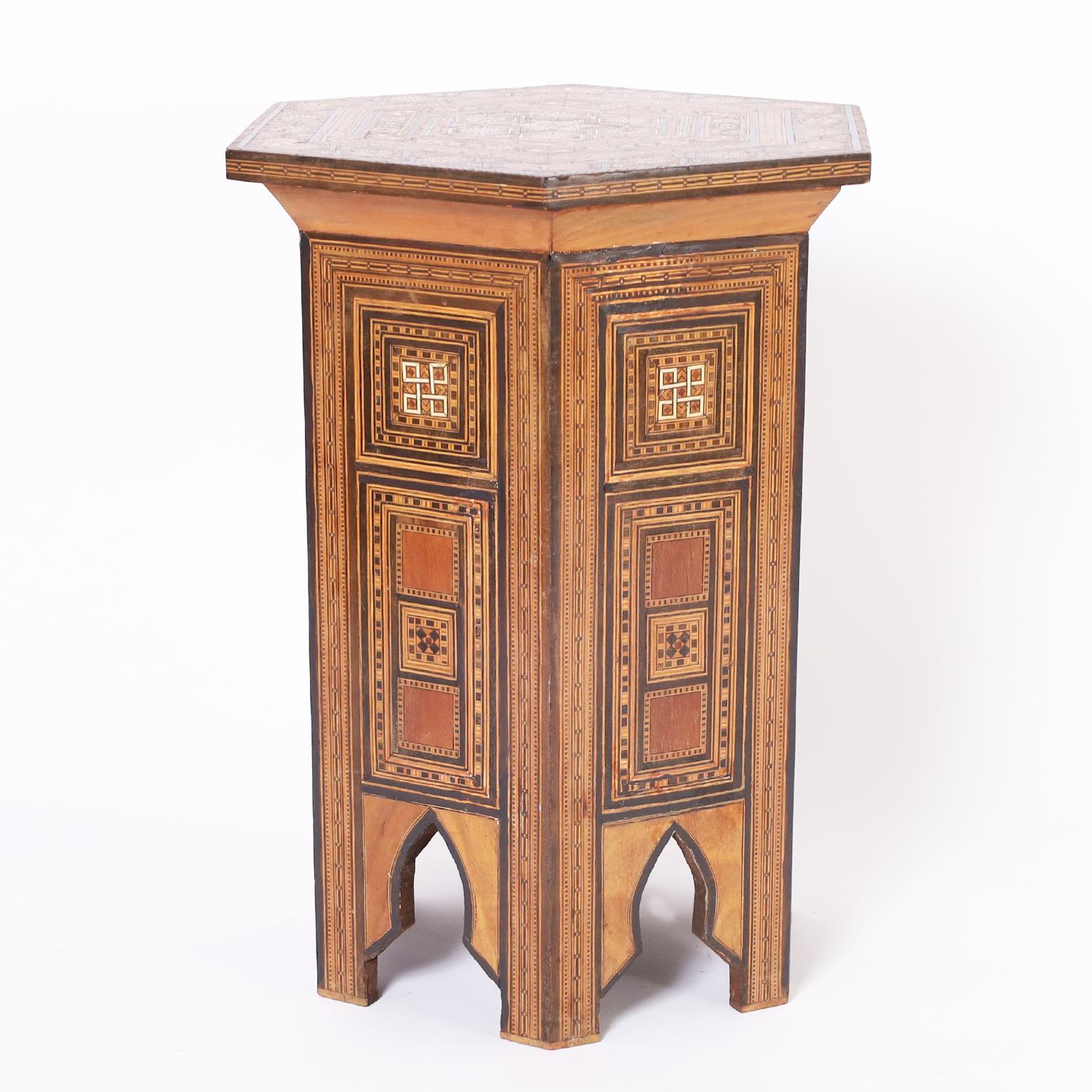 Standout antique Moroccan stand or table crafted in walnut in a hexagon form with elaborate inlaid micro mosaic marquetry composed of mother of pearl, bone, ebony and mahogany on the top and sides. The six legs are divided by moorish arches. As seen
