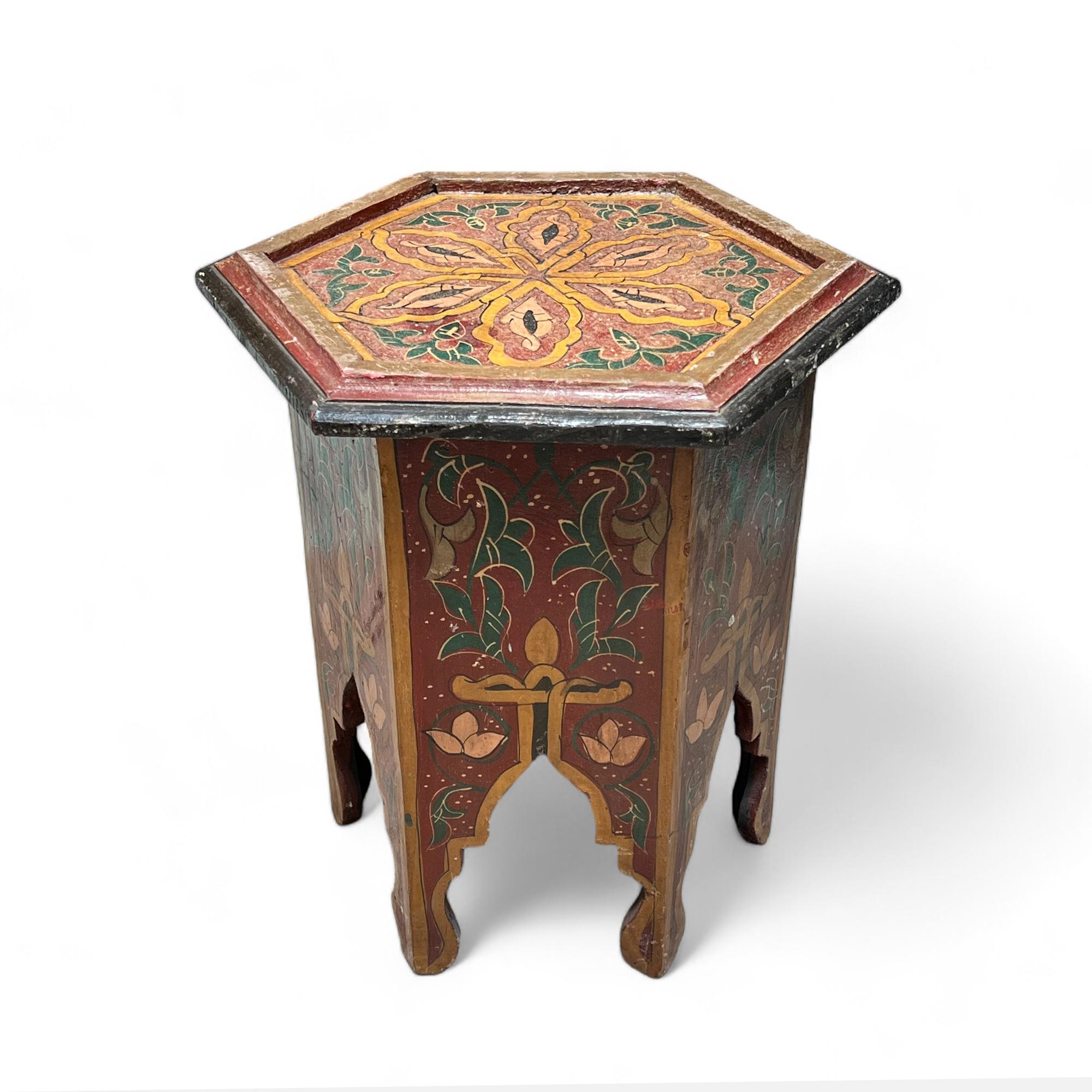 This exquisite Moroccan inlay side table features a hexagonal shape and is adorned with hand-painted floral motifs in vibrant earthy tones. The intricate detailing and craftsmanship make it a perfect accent piece for adding a touch of exotic