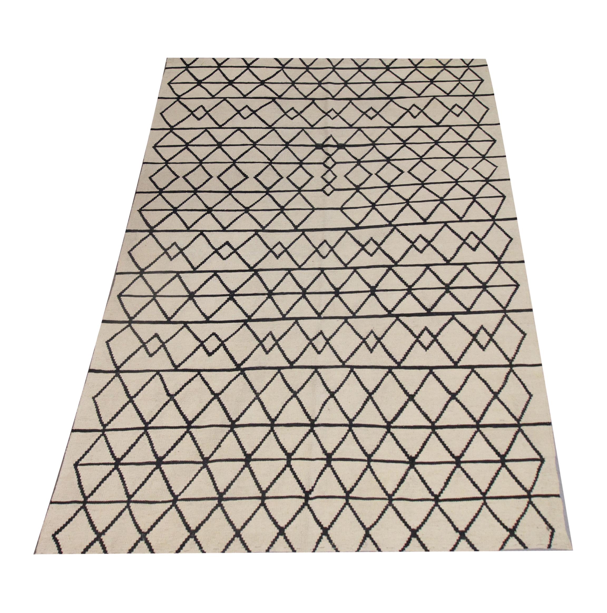 This bold wool area rug is a handwoven kilim constructed in Afghanistan in the early 2000s. The design has been woven with a simple cream background with a contrasting black linear design that makes up the repeating geometric diamond pattern,