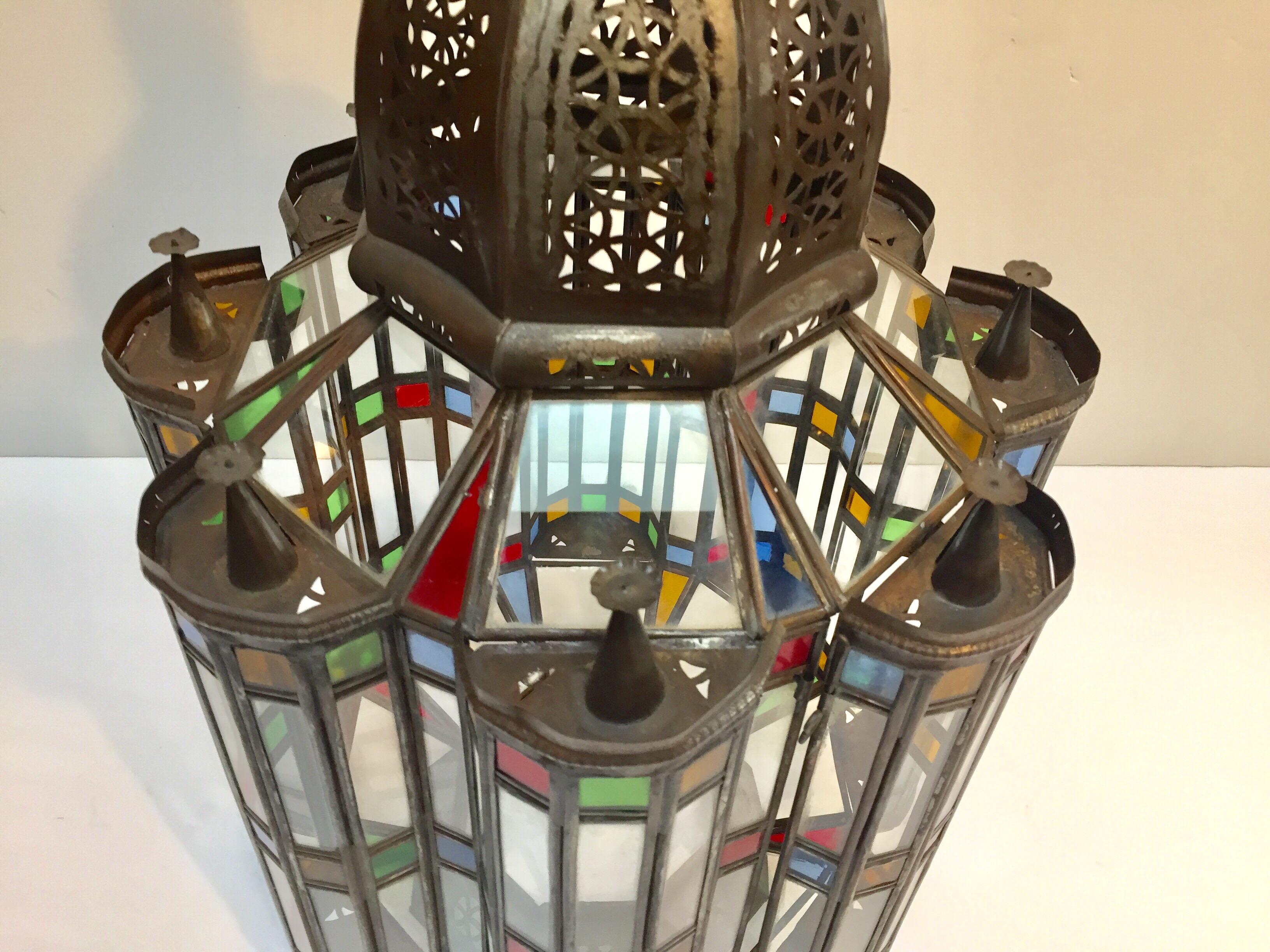 Large glass Moroccan Mamounia lantern with Moorish design.
Elegant Impressive intricate pierced metal and glass Moroccan lantern, 29 inches tall with clear, blue, green, red and gold blown glass all around.
Very fine craftsmanship, antiqued bronze