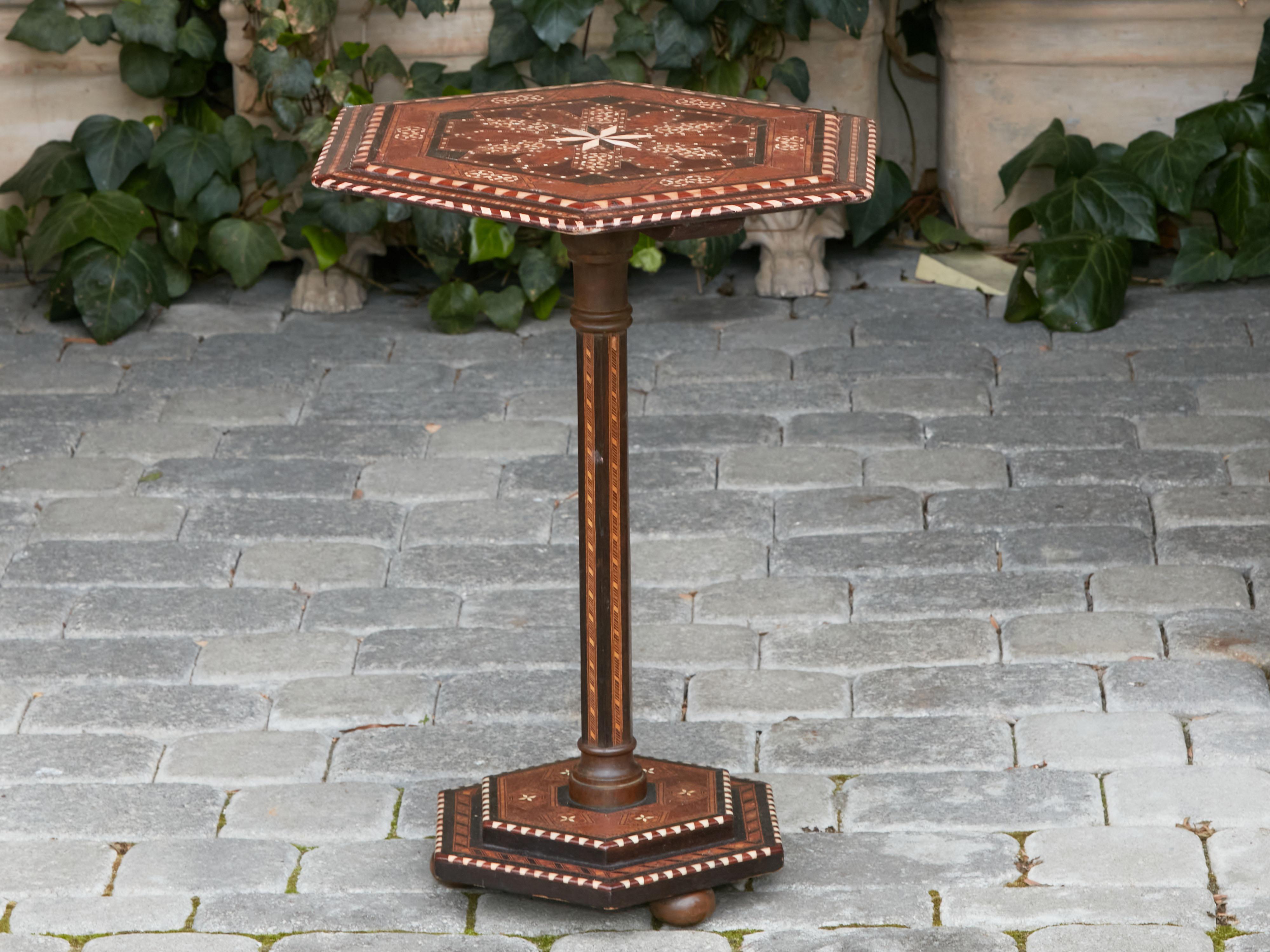 A vintage Moroccan guéridon side table from the mid 20th century, with hexagonal top and geometric inlay. Created in Morocco during the Midcentury period, this charming guéridon features an hexagonal top adorned with a delicate inlay of various