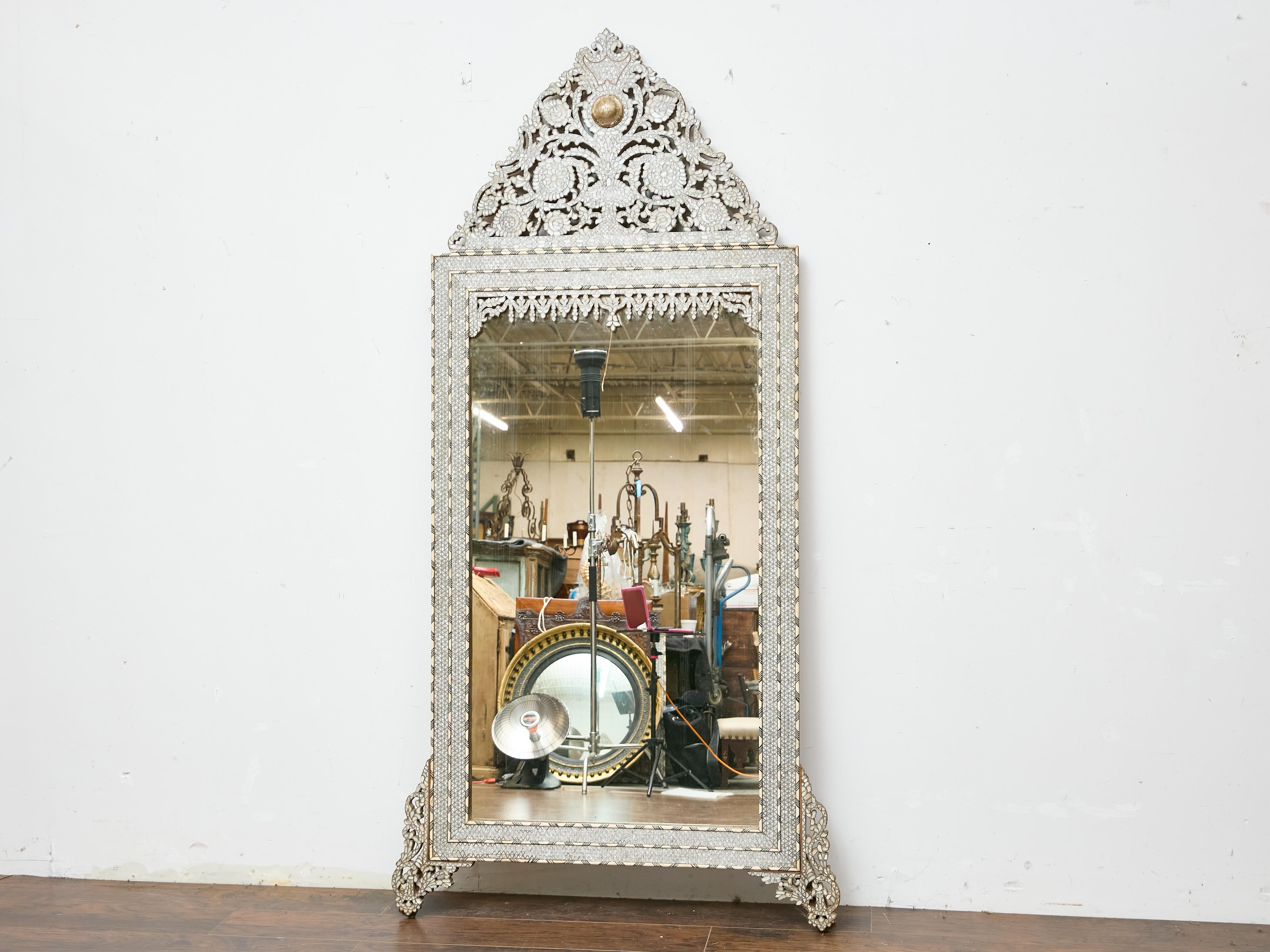An exceptional Moroccan mirror dating to circa 1900, featuring a tall rectangular form surmounted by a distinctive arched crest and resting on pierced bracket feet. The surface is richly adorned with intricate inlay work combining bone and
