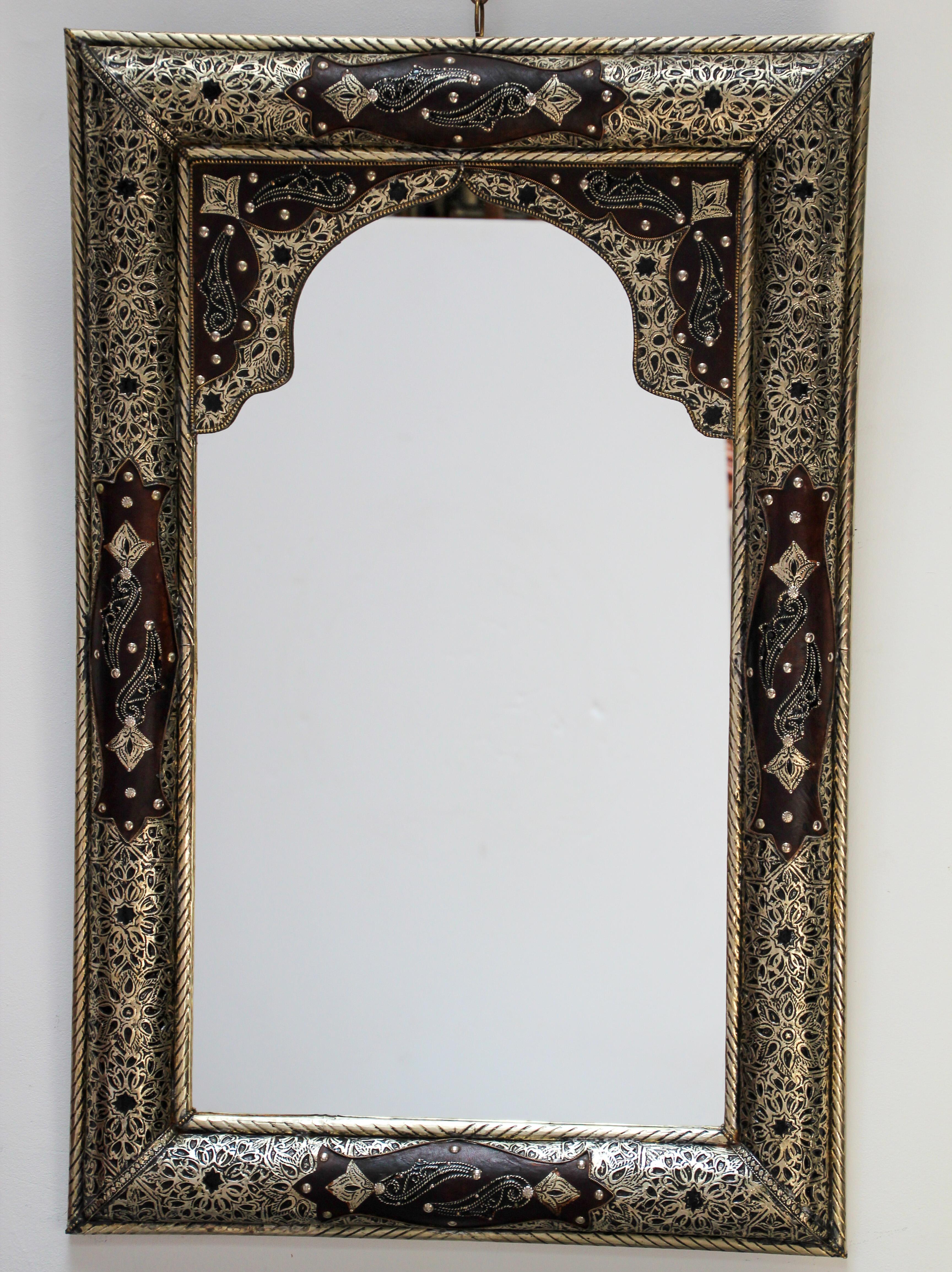 Moroccan mirror decorated with silvered hammered and repousse metal delicately engraved and wrapped with leather.
The inside mirror has a Moorish arch in leather and fine filigree silver décor.
Handcrafted rectangular Orientalist mirror.
Artisan