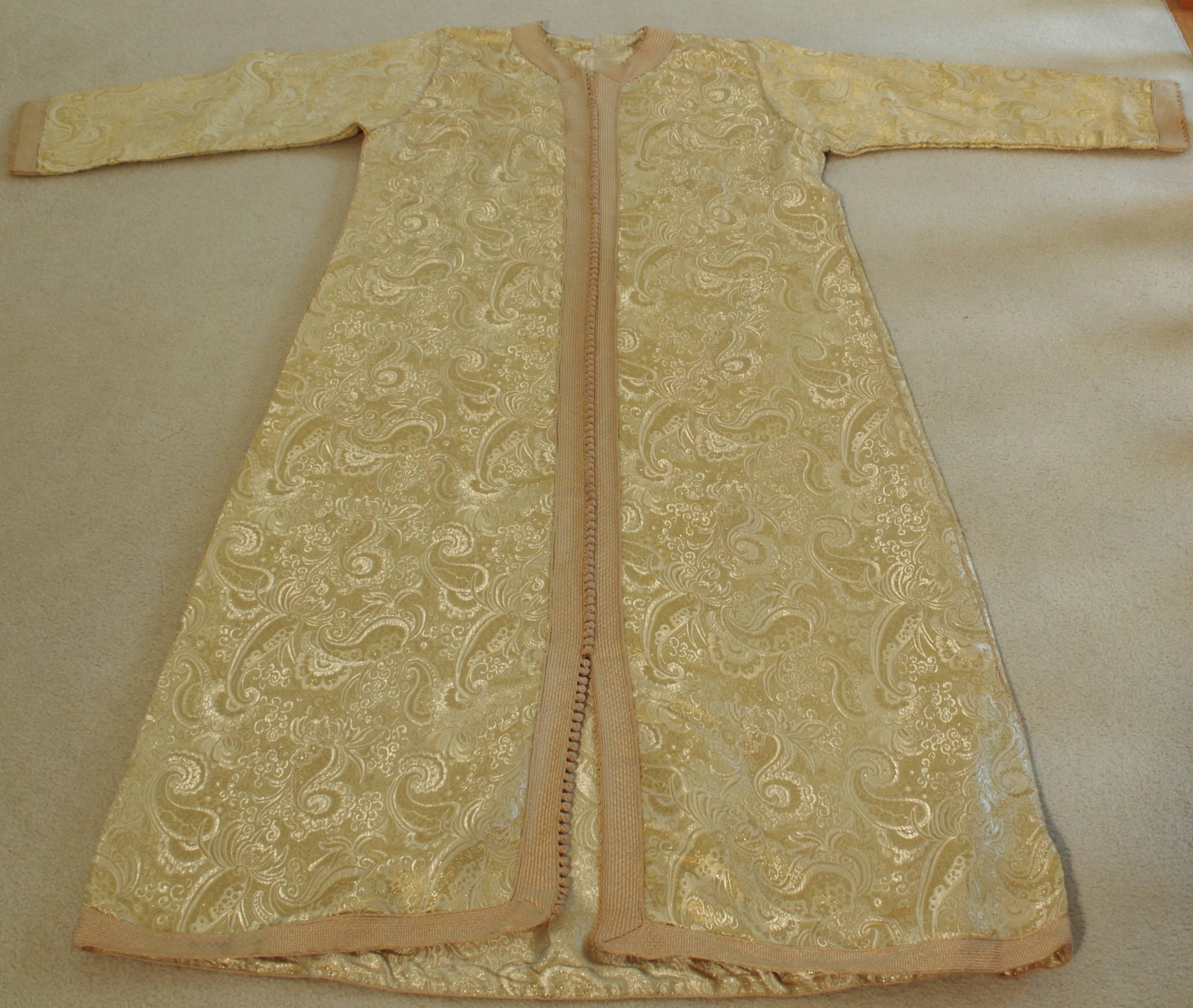 Robe caftan marocaine vintage exotique en brocart métallique, circa 1970.
Le luxueux caftan mauresque est conçu avec de l'or brillant et du brocart métallique vert et de la broderie verte.
L'avant de l'élégante robe caftan est orné à l'avant de