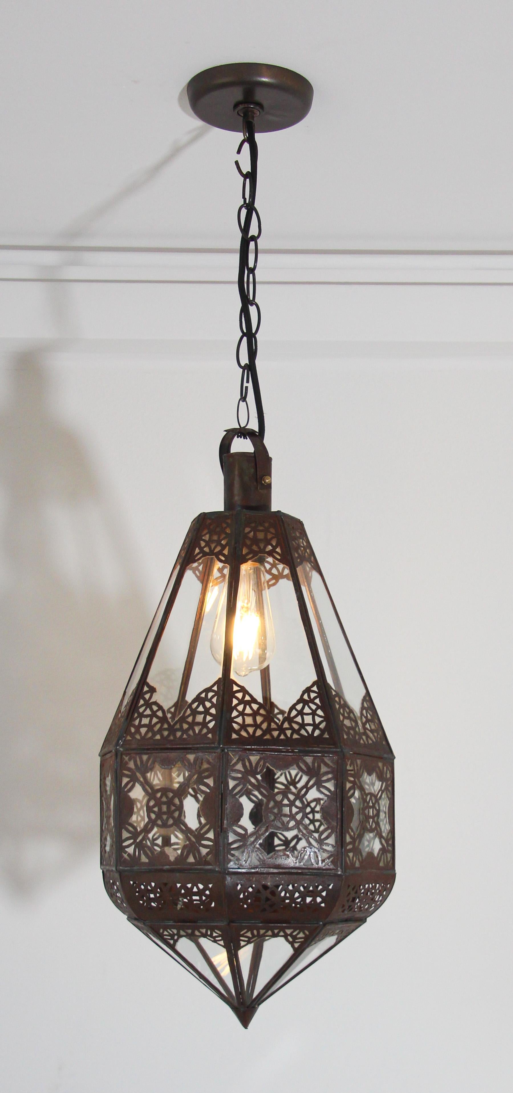Stylish handcrafted Moroccan lantern in clear glass.
Antique bronze rust finish metal with Moorish filigree openwork design.
Moroccan lantern handmade by artisans in Marrakech, Morocco, North Africa.
Dimension: Glass and metal lantern 24 in. height