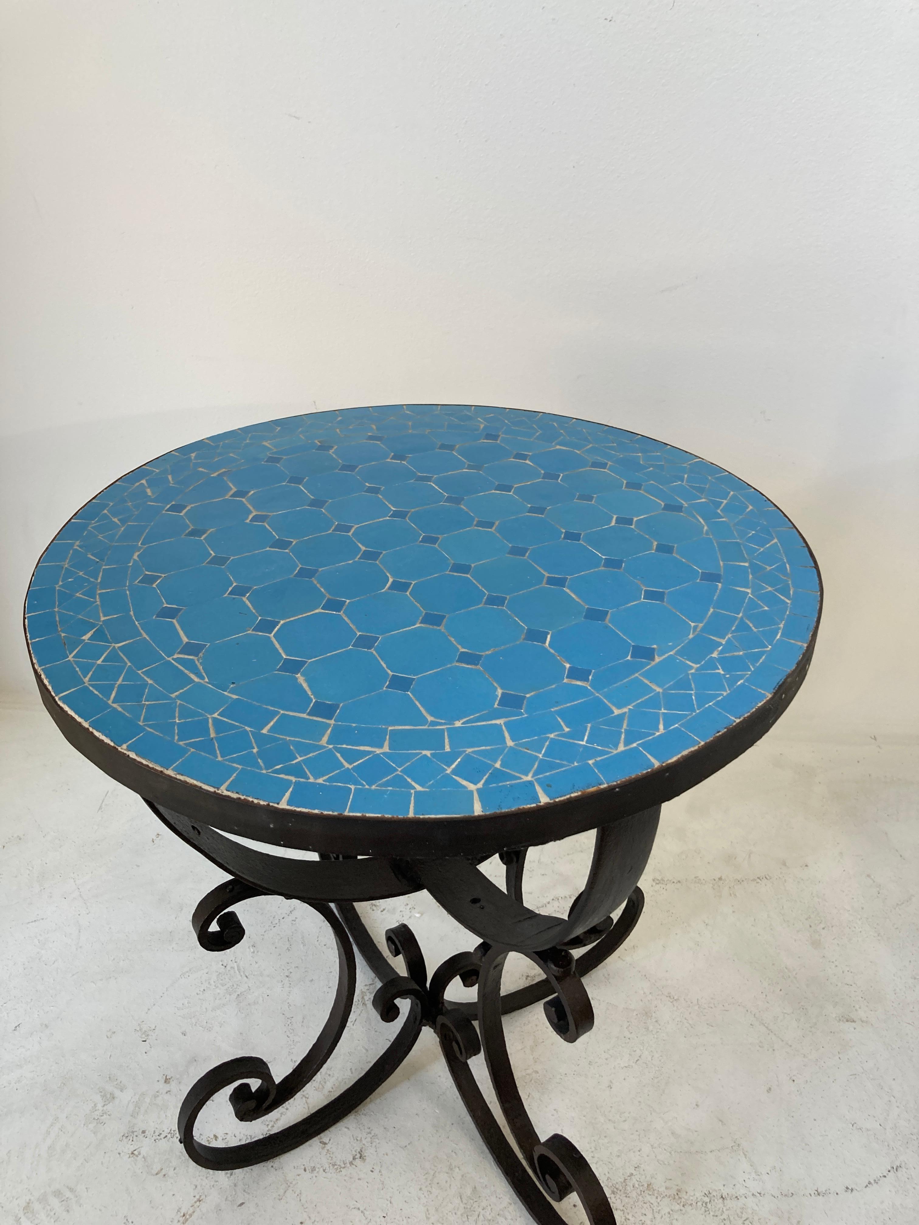 Moroccan Moorish mosaic tile table on wrought iron base.
Handmade by expert artisans in Fez, Morocco using reclaimed old glazed blue colors tiles inlaid in concrete using reclaimed old glazed tiles and making beautiful geometrical designs, colors