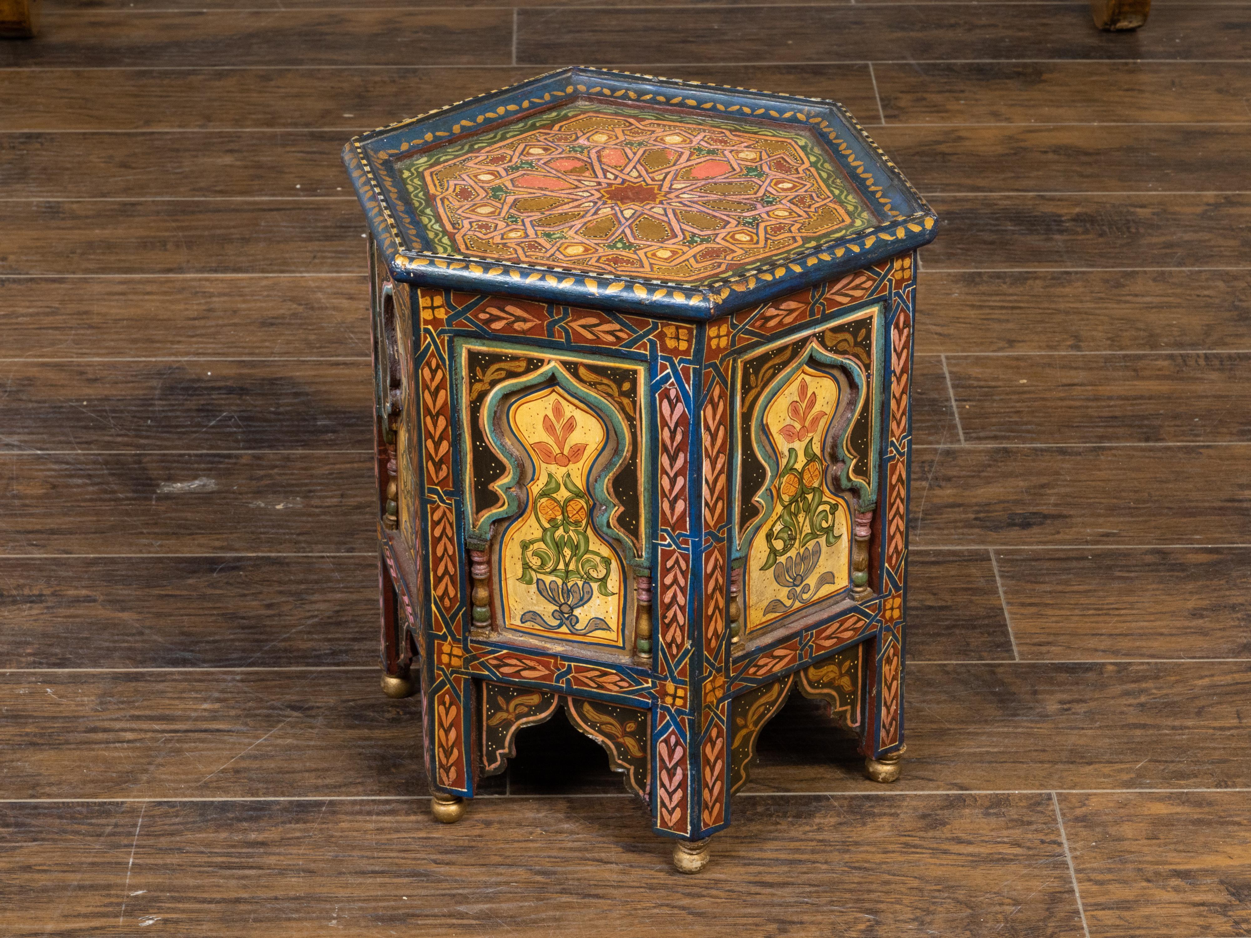 A Moroccan Moorish style drinks table from the early 20th century, with painted geometric motifs, hexagonal top, polychrome décor and carved flaming motifs. Created in Morocco during the first quarter of the 20th century, this petite side table