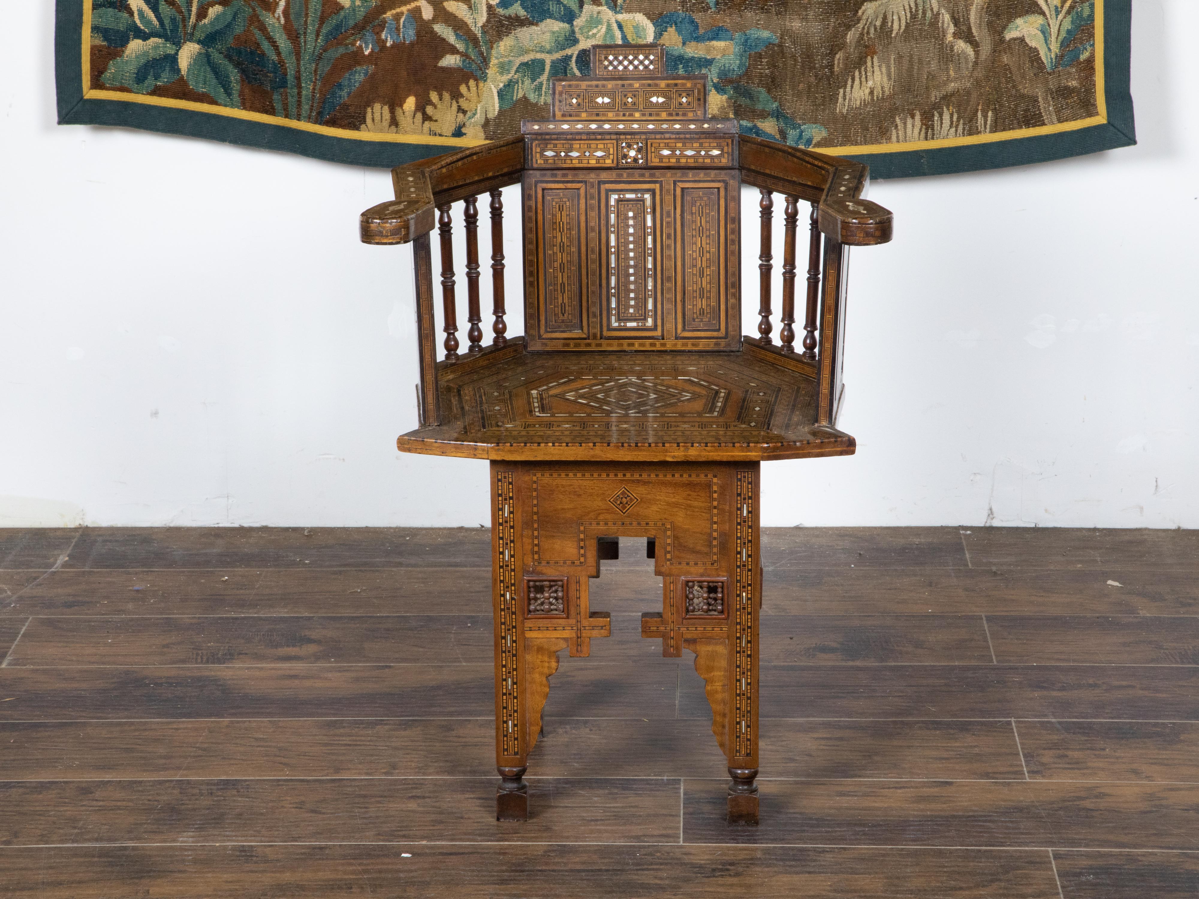 A Moroccan Moorish style armchair from the early 20th century in the manner of Carlo Bugatti, with mother of pearl inlay, geometric décor and carved base. Hand crafted in Morocco in during the first quarter of the 20th century, this Moorish style