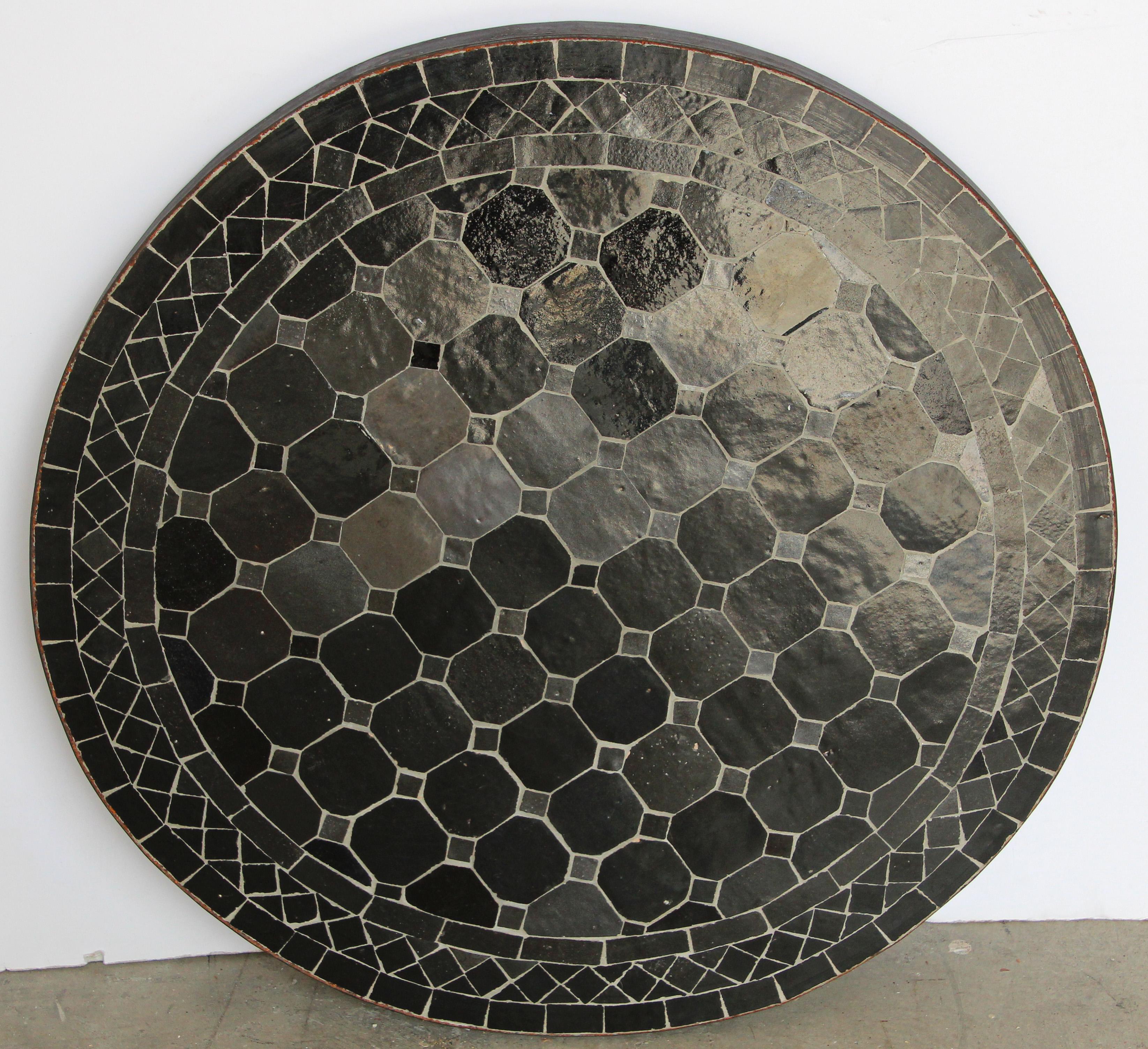 Moroccan mosaic tiles bistro table on iron base.
Handmade by expert artisans in Fez, Morocco using reclaimed old glazed anthracite black color tiles inlaid in concrete using reclaimed old glazed tiles and making beautiful geometrical designs,