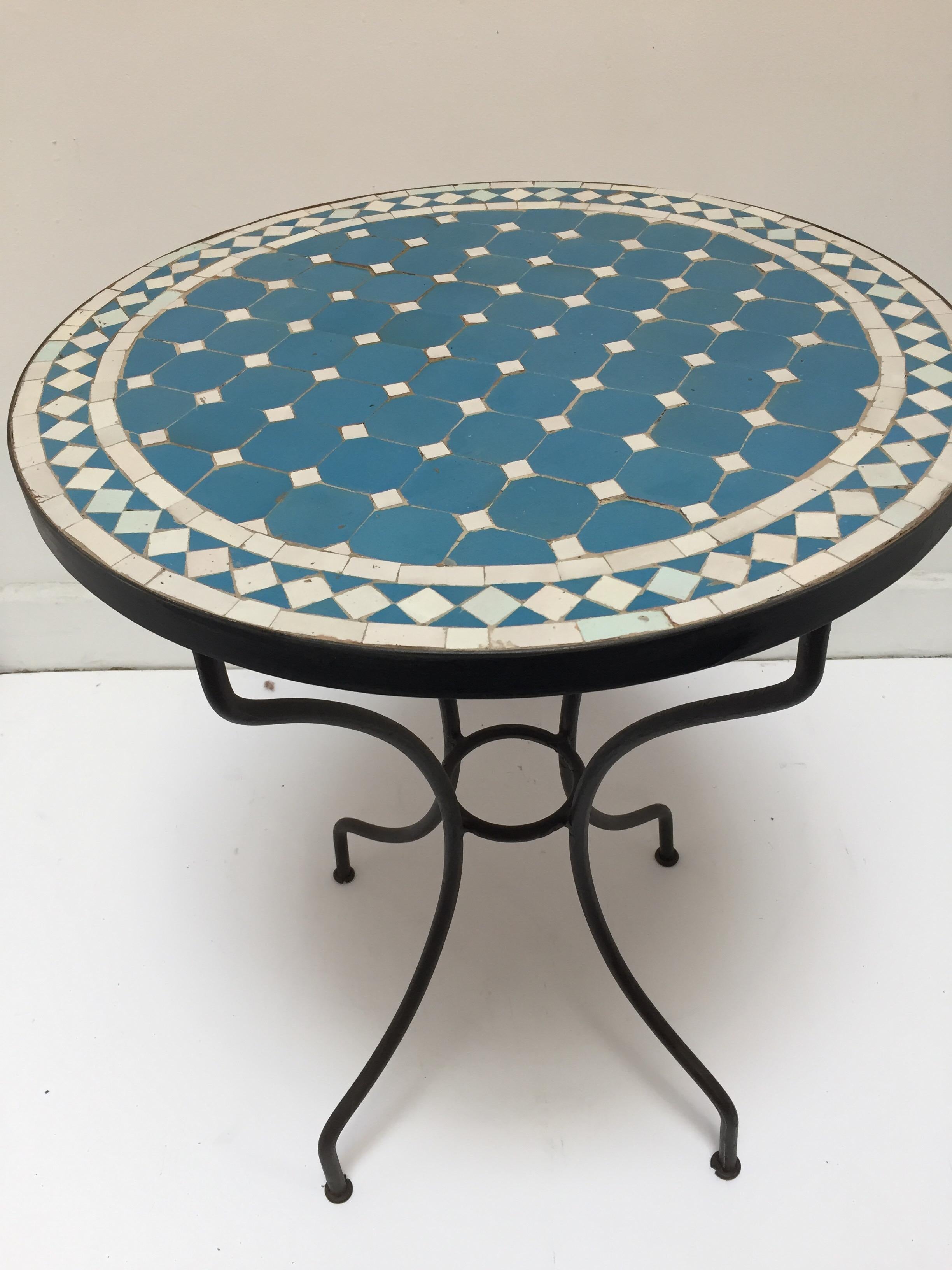 Moroccan mosaic tile bistro table on iron base.
Handmade by expert artisans in Fez, Morocco using reclaimed old glazed blue and tan tiles inlaid in concrete using reclaimed old glazed tiles and making beautiful geometrical designs, colors are