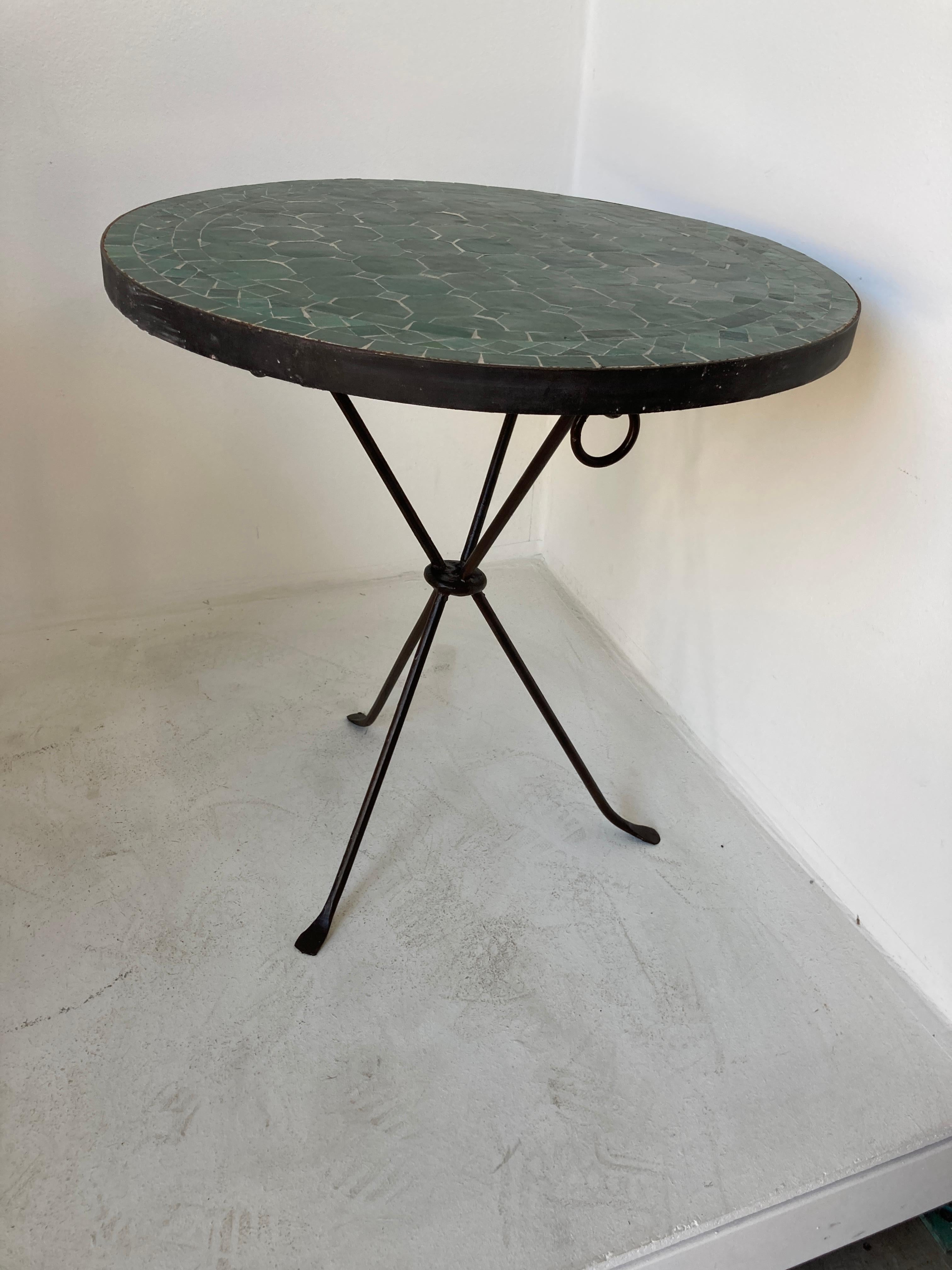 Moroccan Moorish mosaic tile table on wrought iron scrolled base.
Handmade by expert artisans in Fez, Morocco using reclaimed old glazed emerald green colors tiles inlaid in concrete using reclaimed old glazed tiles and making beautiful geometrical