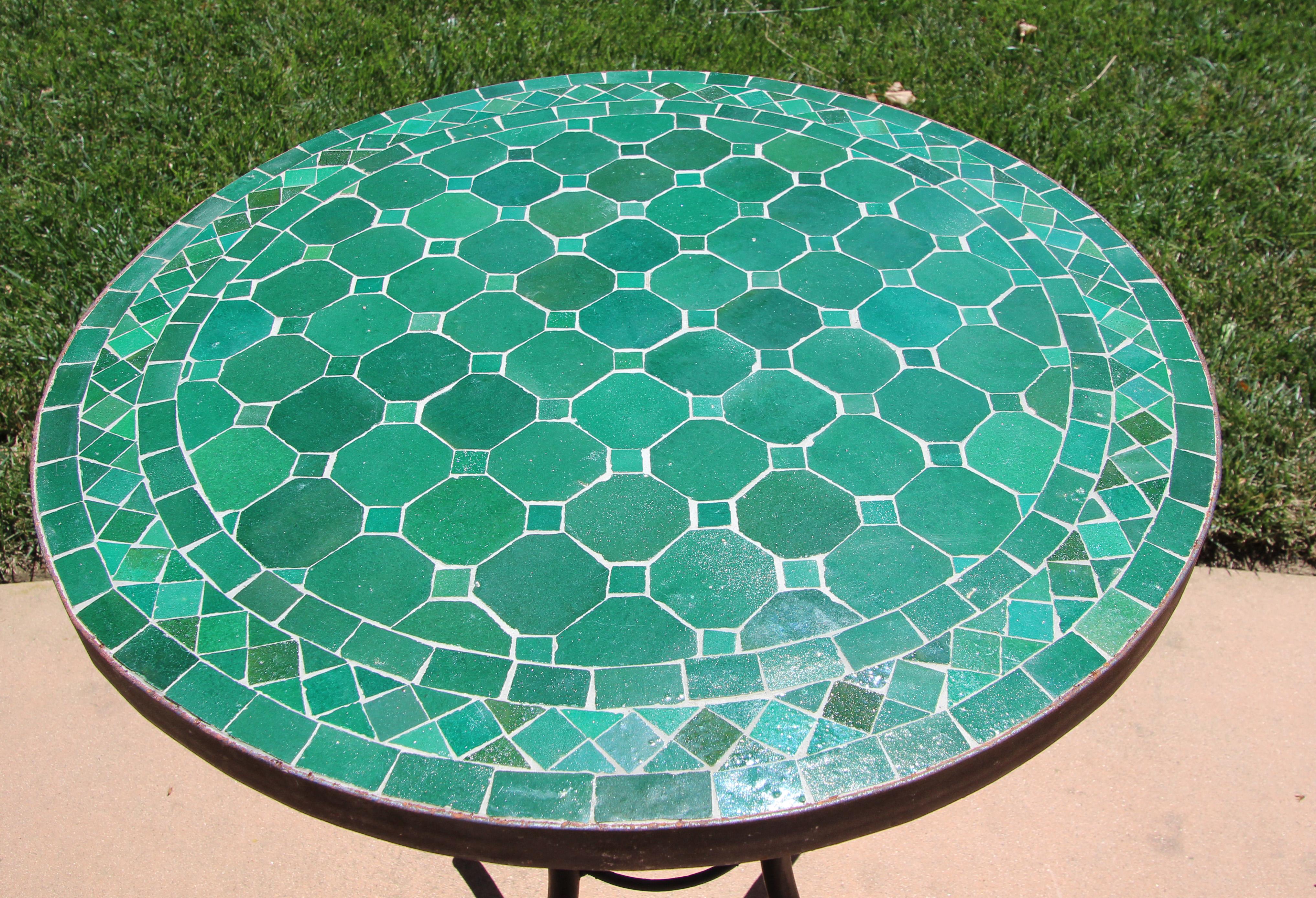 Moroccan mosaic tile bistro table on iron base. 
Handmade by expert artisans in Fez, Morocco using reclaimed old glazed blue and tan tiles inlaid in concrete using reclaimed old glazed tiles and making beautiful geometrical designs, colors are