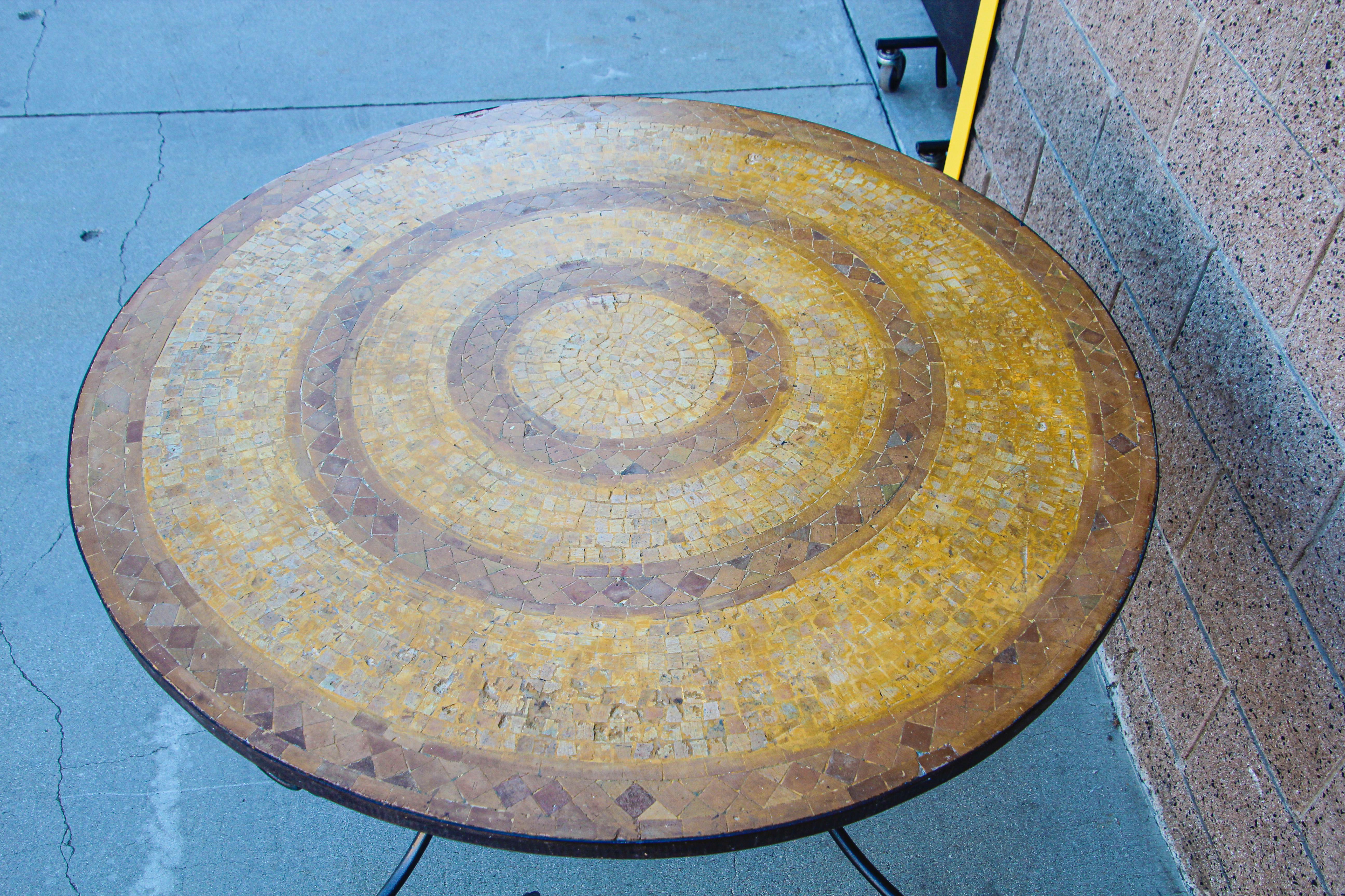 A inlaid round stone Moroccan mosaic tile tabletop on a wrought iron base.
Handcrafted in Morocco could be use indoor or outdoor.
Spanish Moorish garden dining mosaic table in the style of Bill Willis Marrakech.
The top is not attached to the