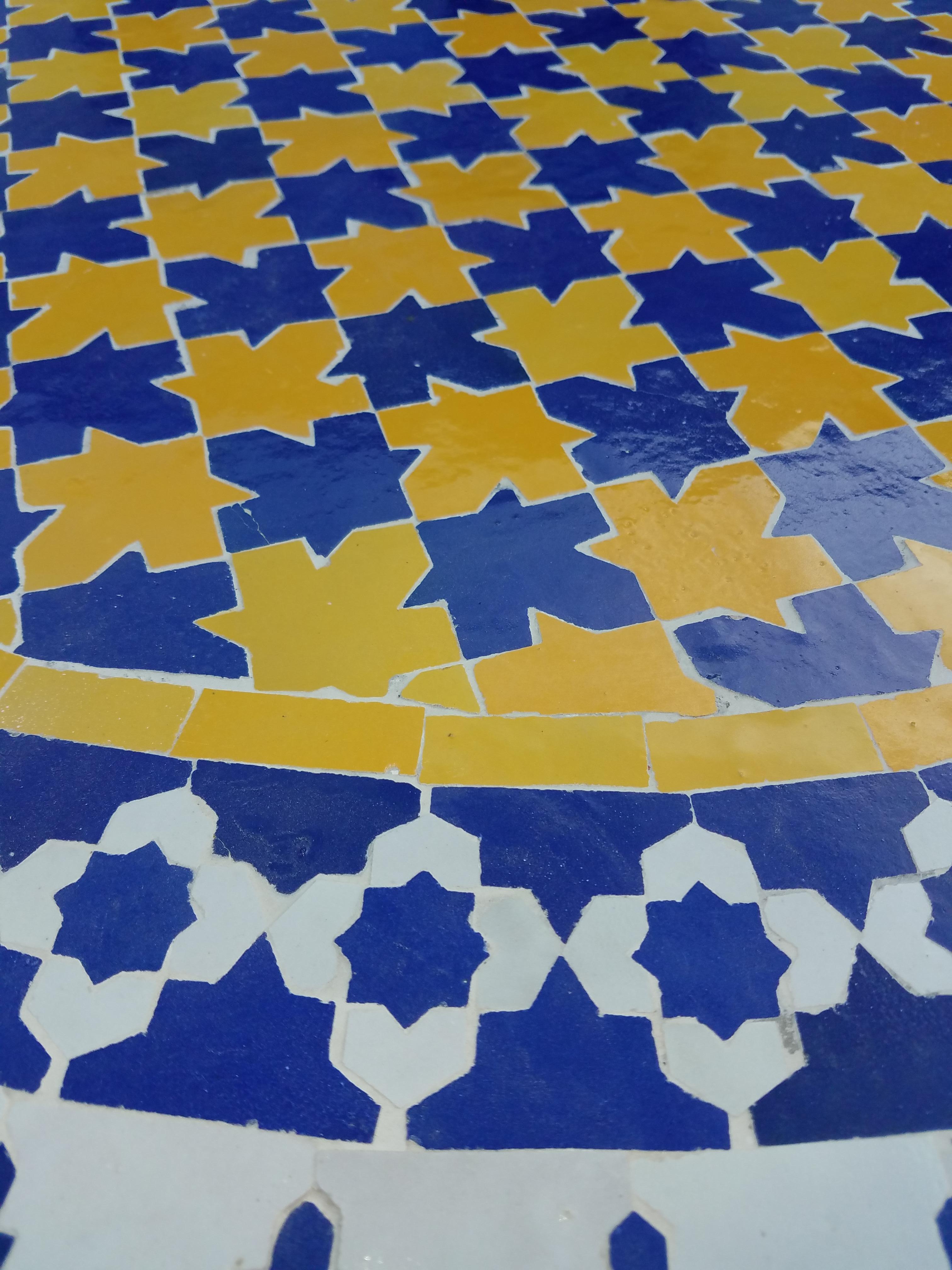 Moroccan multicolor mosaic tile table. An indoor / outdoor table of measuring approximately 48 inches in diameter. Outstanding colors and handcraftsmanship. Colors are cobalt blue, gold yellow, and off-white. Included in the price is a sturdy