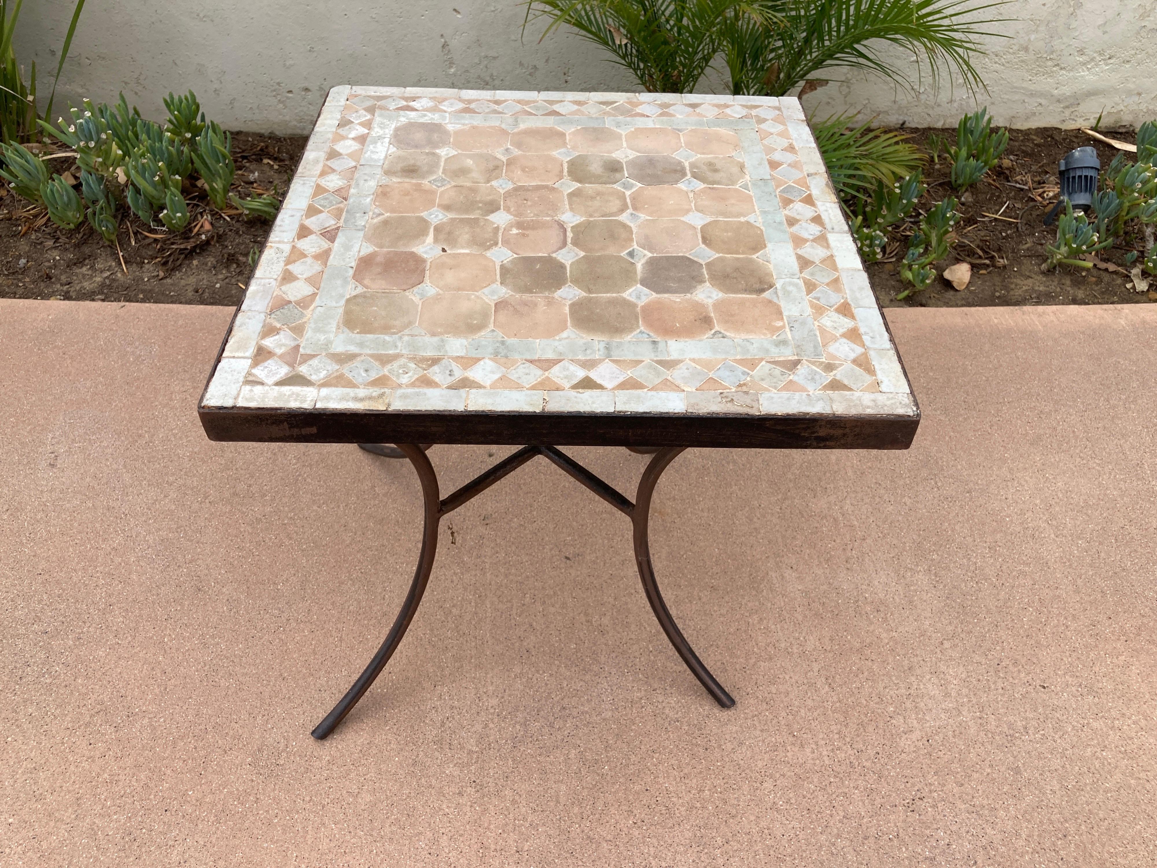 Moroccan mosaic tile square table on iron base. 
Handmade by expert artisans in Fez, Morocco using reclaimed old glazed ivory and tan tiles inlaid in concrete using reclaimed old glazed tiles and making beautiful geometrical designs, the iron base